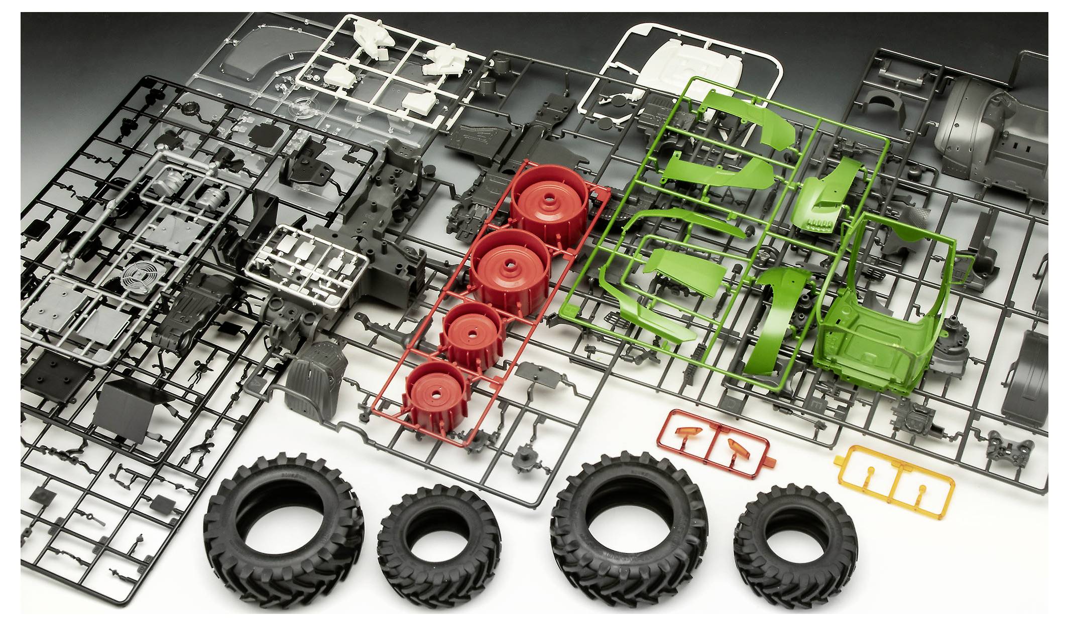 Modellbausatz-Teile für einen Traktor, einschließlich Räder, Fahrgestell und Karosseriekomponenten in schwarzen, roten und grünen Kunststoffrahmen.