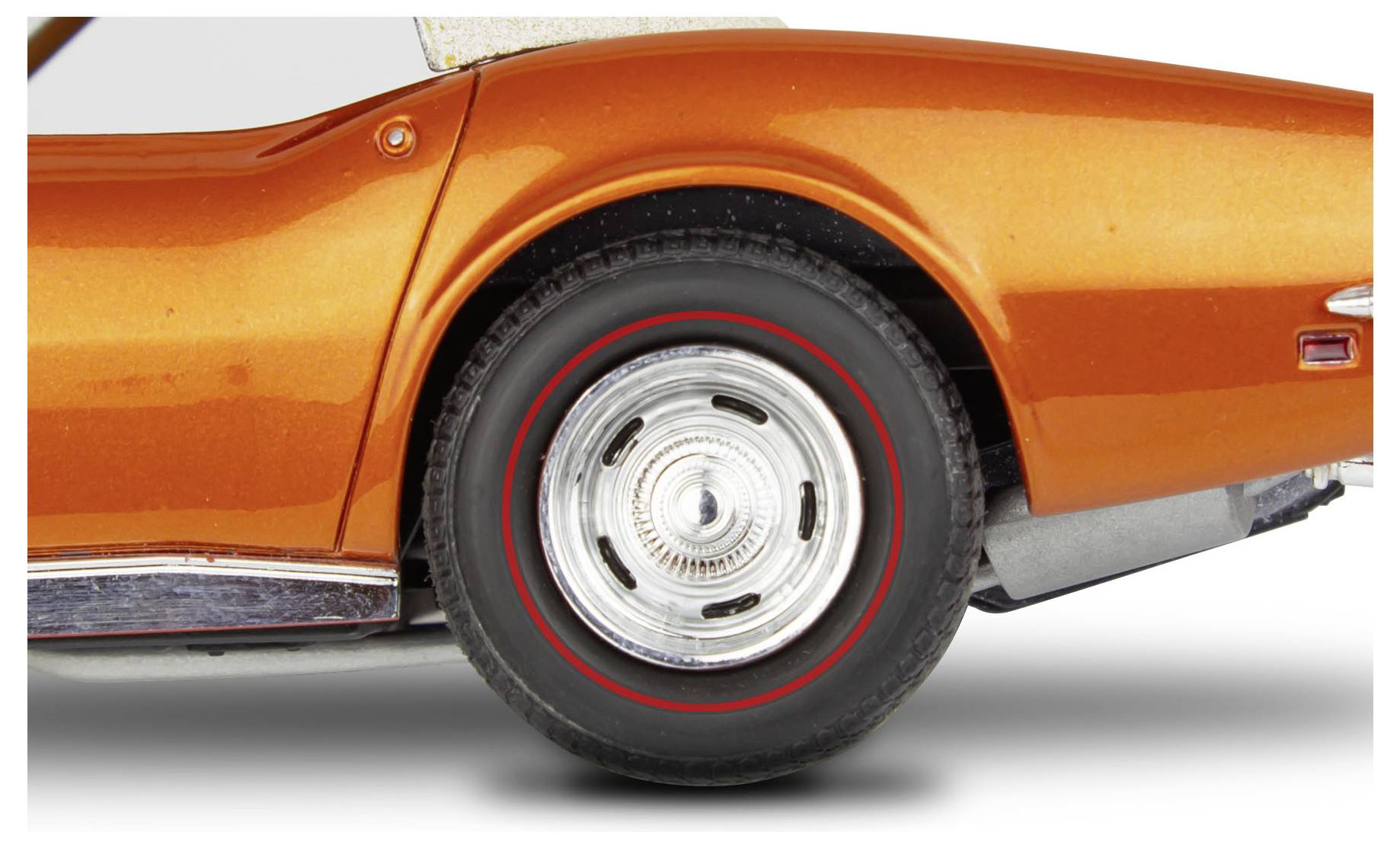 Nahaufnahme des Hinterrads eines orangefarbenen Oldtimers, die detaillierte Ansichten des Reifens und des Chromfelgenrands vor einem weißen Hintergrund zeigt.