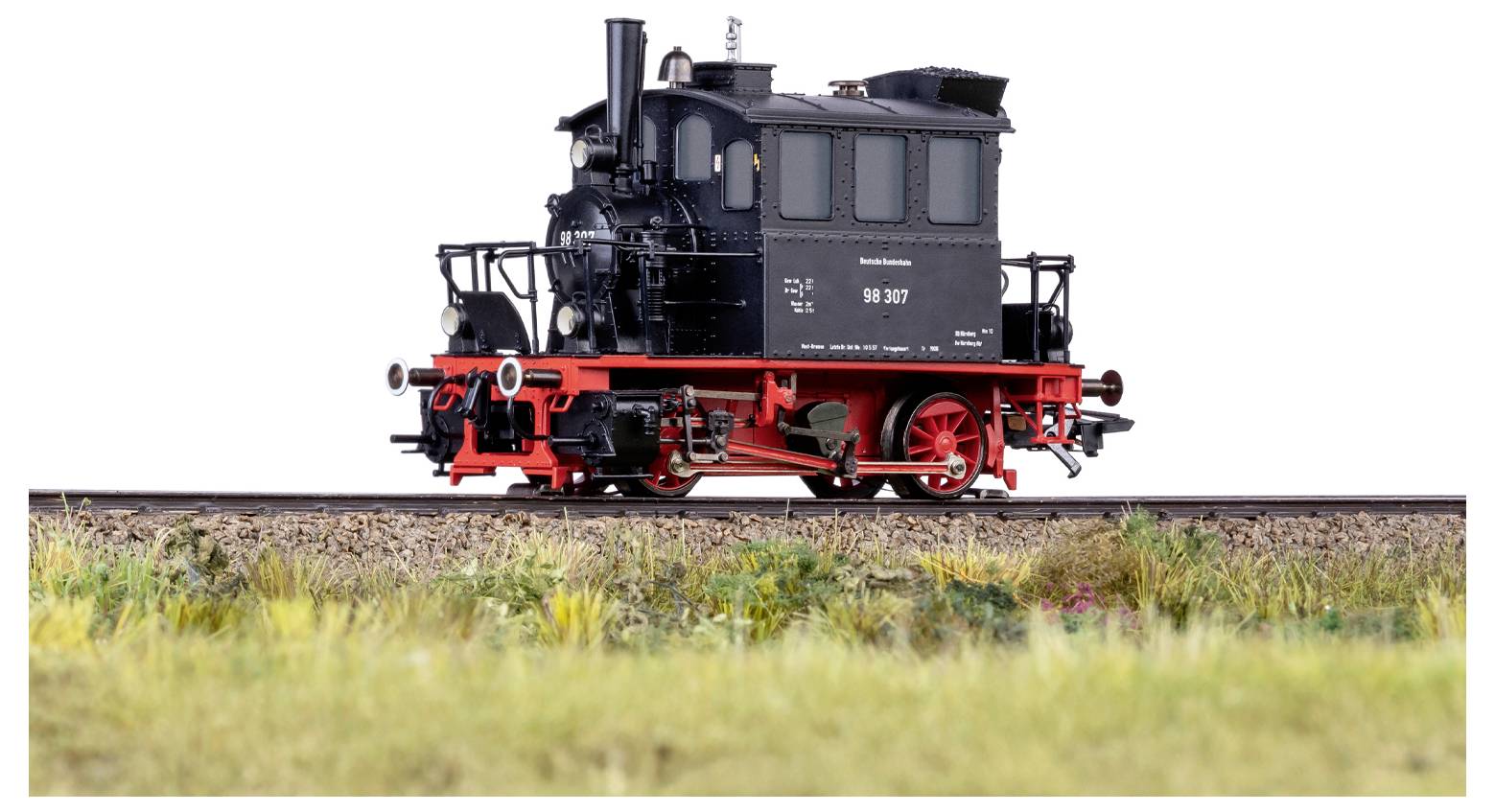 Ein detailliertes Modell einer altehrwürdigen schwarzen Dampflokomotive mit roten Rädern, sitzt auf einem Abschnitt von Eisenbahnschienen.