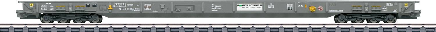 Ein langer, grauer Flachbahn-Güterwaggon mit mehreren Rädern ist zu sehen, an dessen Seite verschiedene Aufschriften und Symbole angebracht sind. Er steht auf Schienen.