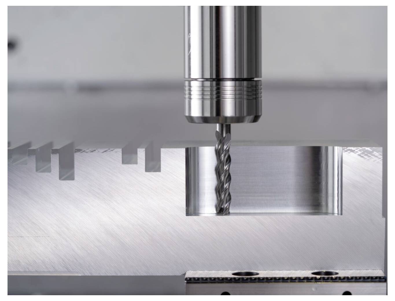 Eine Metallbohrmaschine, die präzise Rillen auf einer flachen Metalloberfläche erzeugt und einen laufenden industriellen Bearbeitungsprozess veranschaulicht.