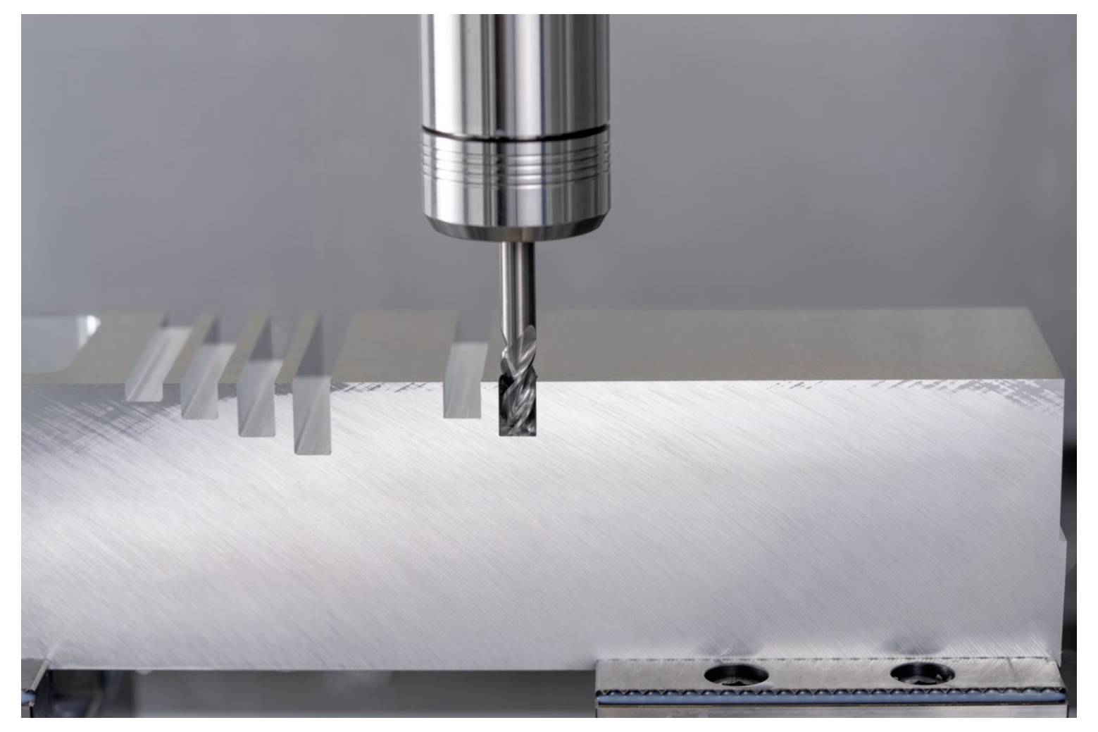 Eine Metallschneidevorrichtung bearbeitet Rillen in einem Aluminiumblock und zeigt präzisionstechnische Ingenieurskunst in einer kontrollierten Umgebung.