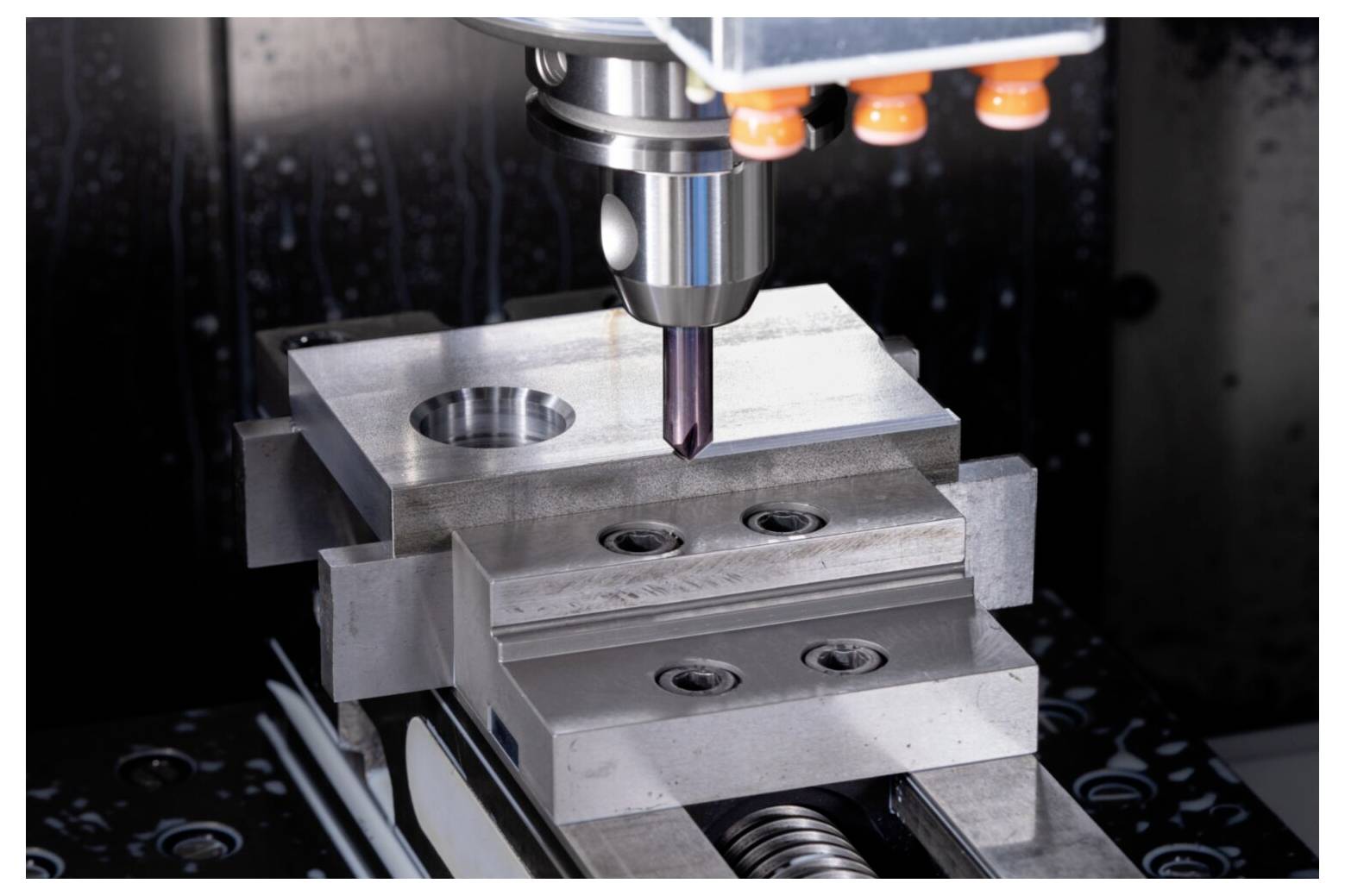 CNC-Maschine, die mit Präzision in einen Metallblock bohrt und dabei den Bearbeitungsprozess und die industrielle Technologie demonstriert.