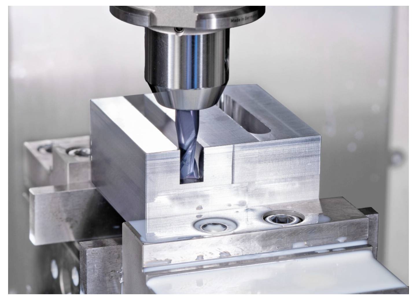 Eine CNC-Maschine fräst präzise einen rechteckigen Metallblock und demonstriert dabei einen laufenden automatisierten industriellen Bearbeitungsprozess.