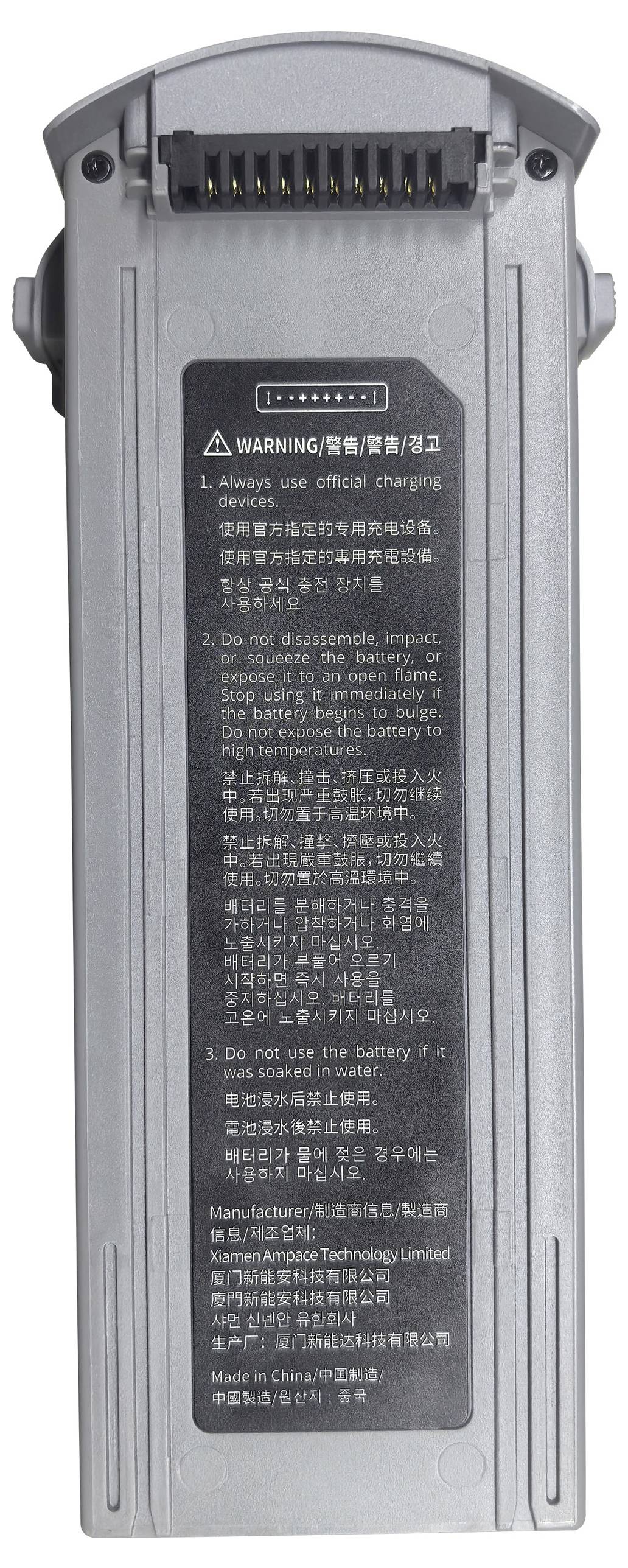 Eine graue Batterie mit Ladekontakten und Warnhinweisen in mehreren Sprachen.