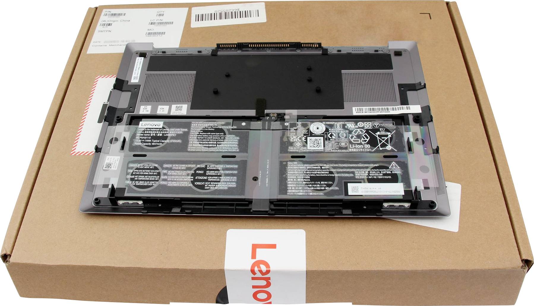 Eine Laptop-Batterie liegt auf einer Lenovo-Verpackung und zeigt Batteriespecifikationen und Sicherheitssymbole.