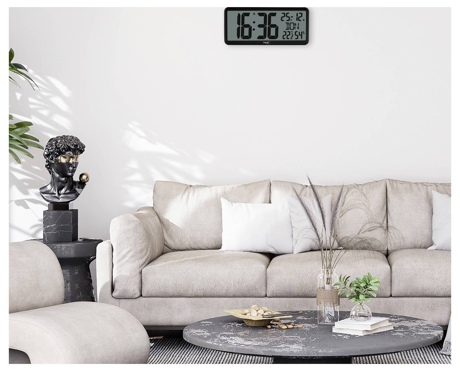 Ein modernes Wohnzimmer mit einem beigen Sofa, einer schwarzen Skulptur auf einem Beistelltisch und einer digitalen Uhr, die '16:36 25.12' anzeigt.