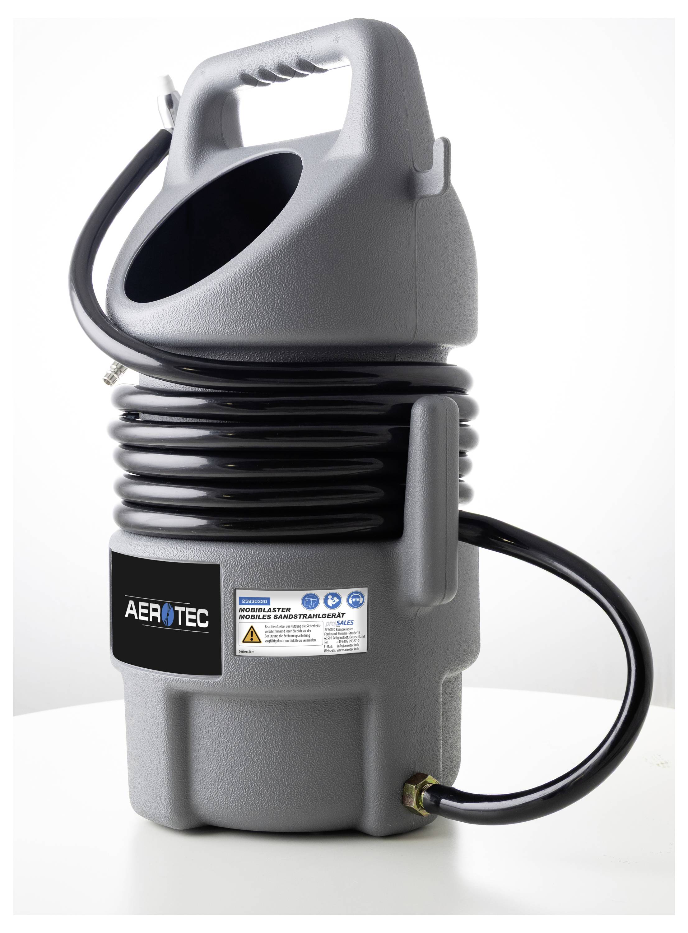 Ein kleiner grauer tragbarer Luftkompressor mit Spiralschlauch und Griff, der auf einem Tisch platziert ist. Das Markenetikett lautet „AEROTEC