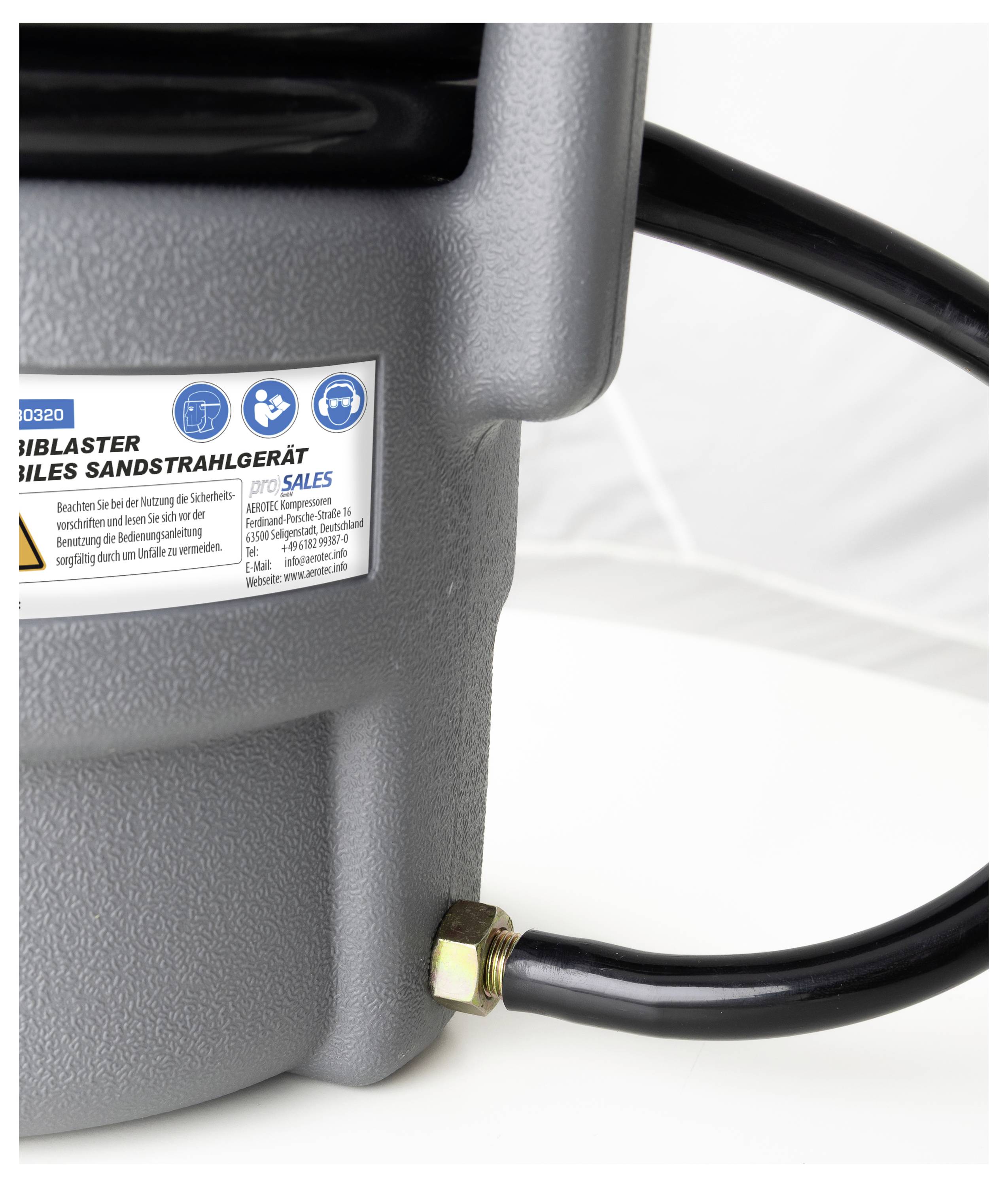 Eine Nahaufnahme eines grauen Industriegeräts mit einem angeschlossenen schwarzen Kabel und einem Etikett mit Betriebsanweisungen und Sicherheitssymbolen.