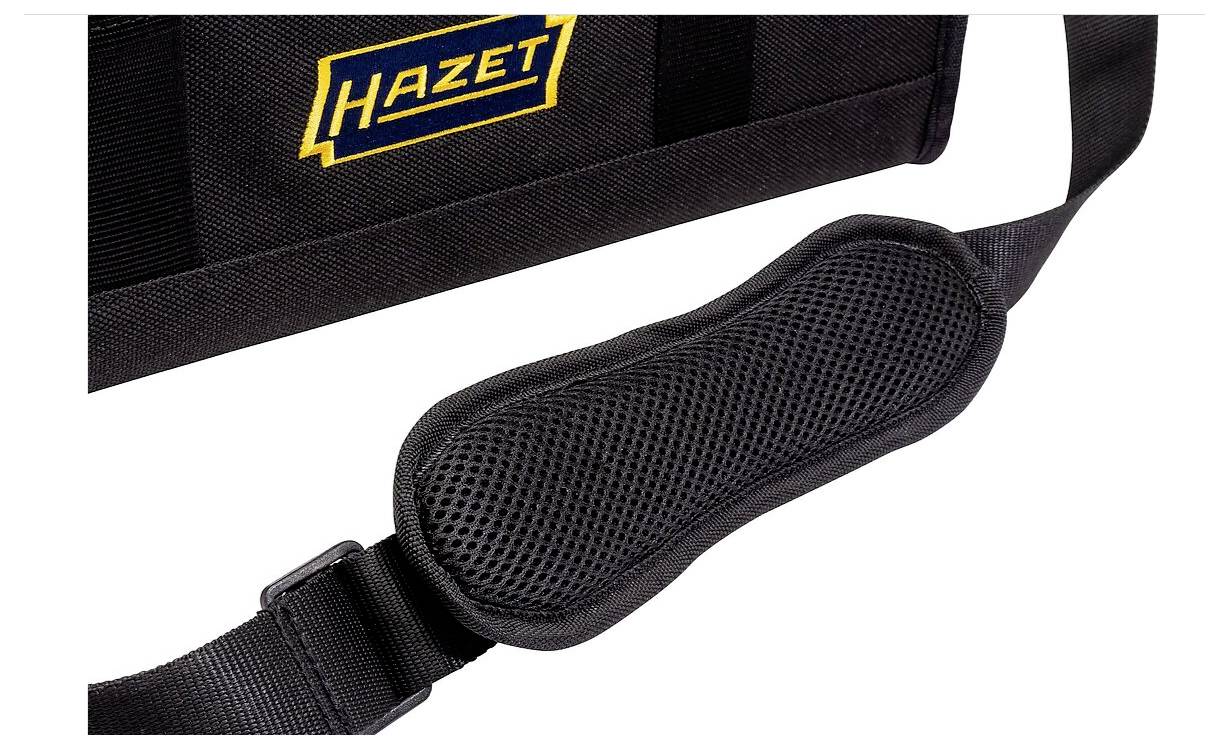 Eine Nahaufnahme eines schwarzen Schultergurts, der an einer Tasche befestigt ist und einen gepolsterten Abschnitt für Komfort aufweist. Die Tasche trägt ein blaues und gelbes 'Hazet' Logo.