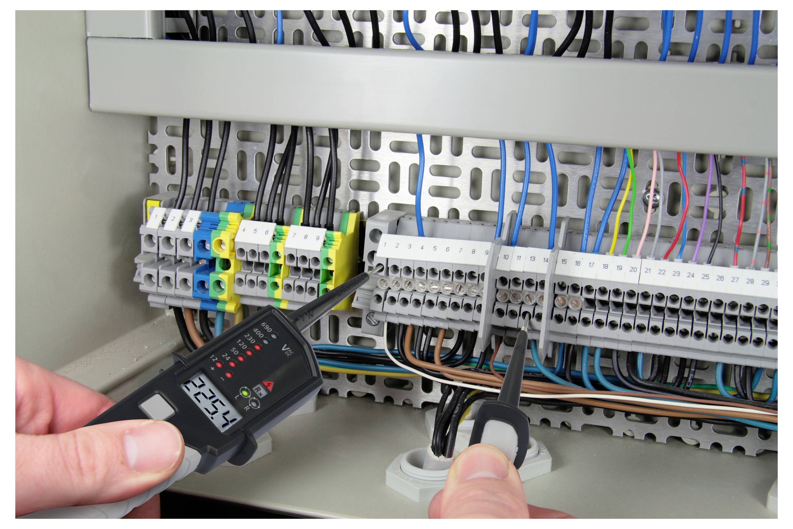Eine Person verwendet ein digitales Multimeter, um elektrische Verbindungen in einer Sicherungsverteilung zu prüfen und die korrekte Spannung und Funktionalität sicherzustellen.