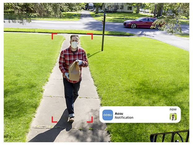 Eine Person mit einer Maske trägt eine Papiertüte auf einem Gehweg zu einem Haus. Eine Benachrichtigung von 'Aosu' zeigt ihre Ankunft an.