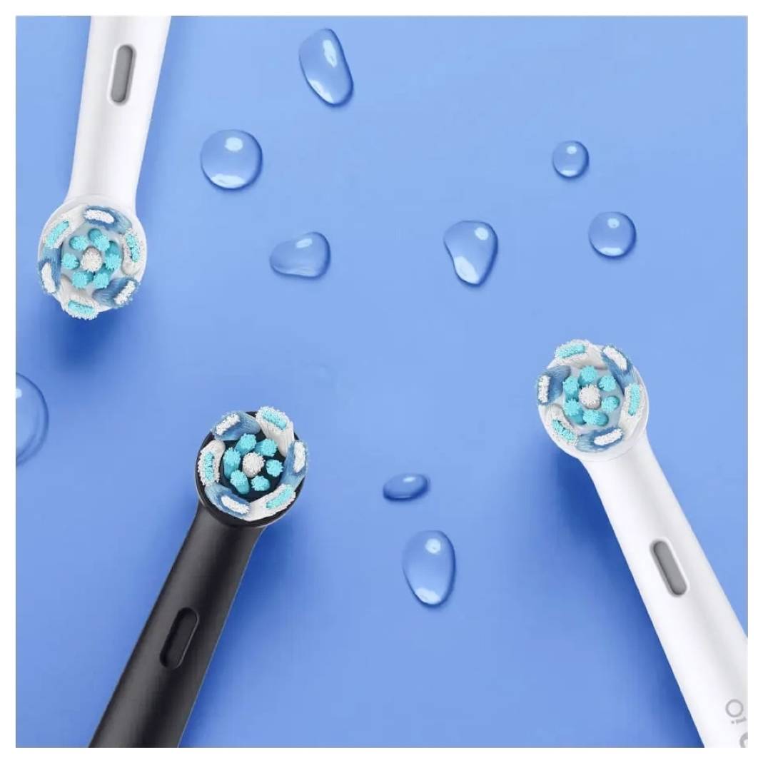 Drei elektrische Zahnbürstenköpfe, zwei weiße und einer schwarz, mit blauen Borsten, angeordnet auf einem blauen Hintergrund mit Wassertropfen.