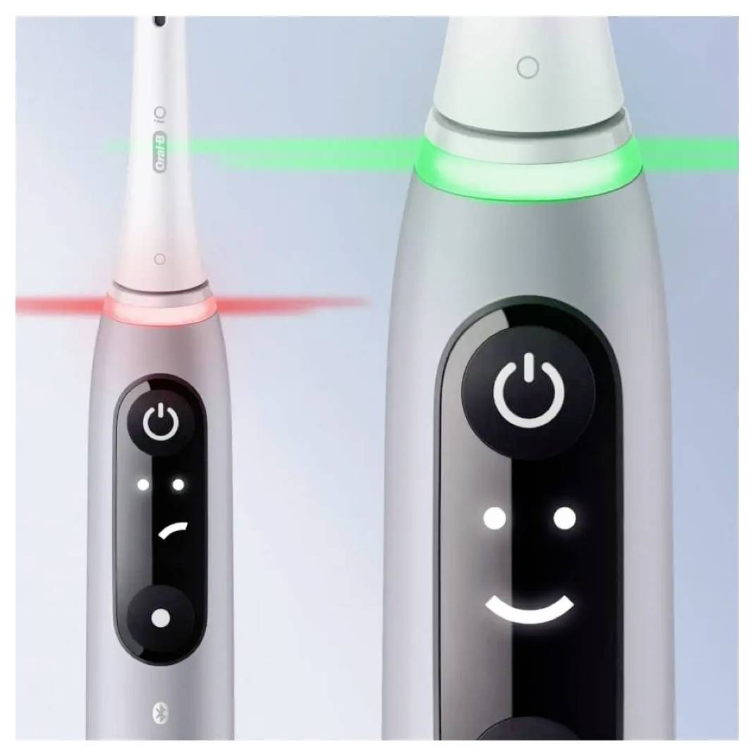 Elektrische Zahnbürsten mit digitalen Displays: Eine zeigt ein rotes Stirnrunzeln, was auf ein Problem hinweist; die andere ein grünes Lächeln, was eine ordnungsgemäße Funktion anzeigt.