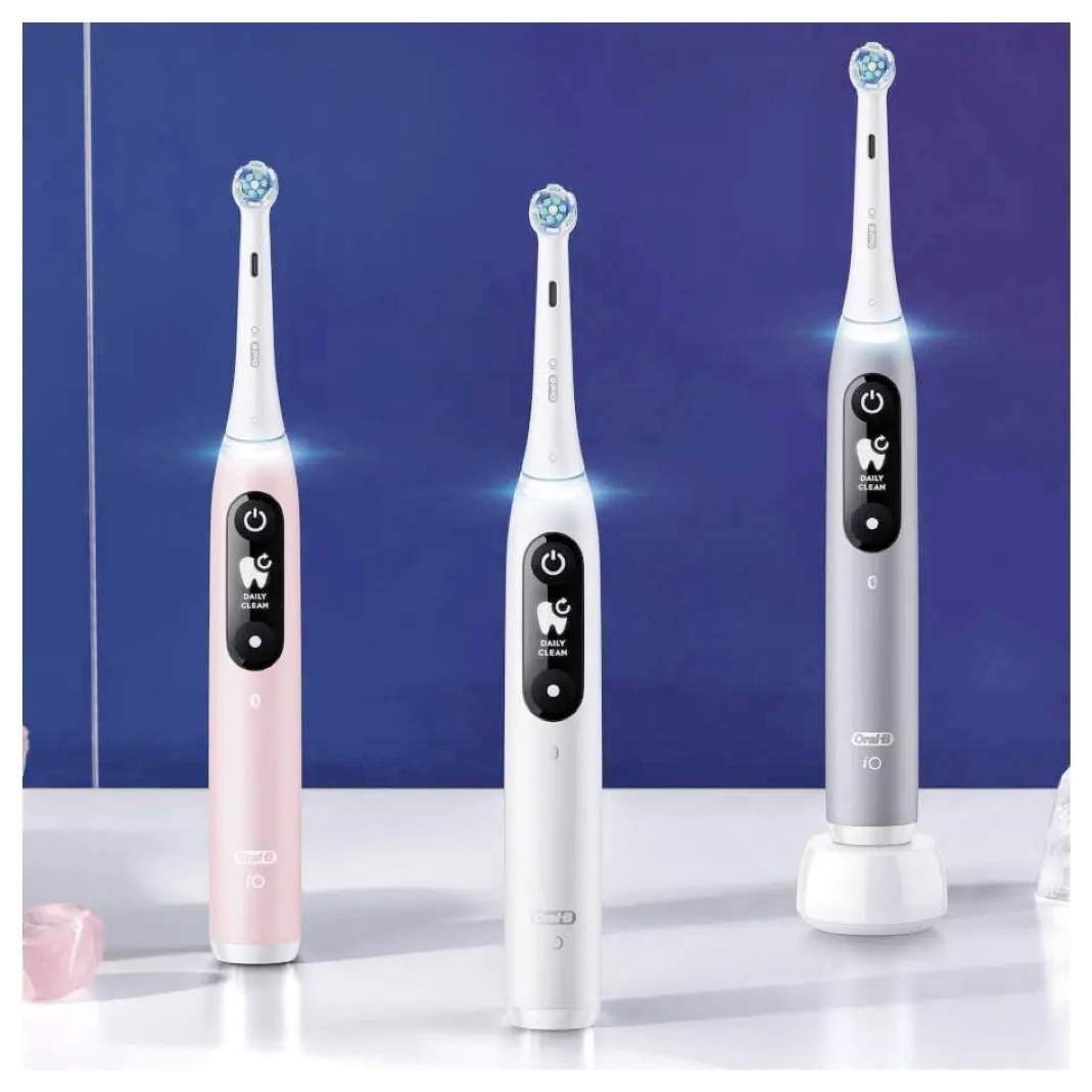 Drei elektrische Zahnbürsten in Rosa, Weiß und Silber mit Einschalttasten und Symbolen auf dem Display, vor einem blauen Hintergrund.