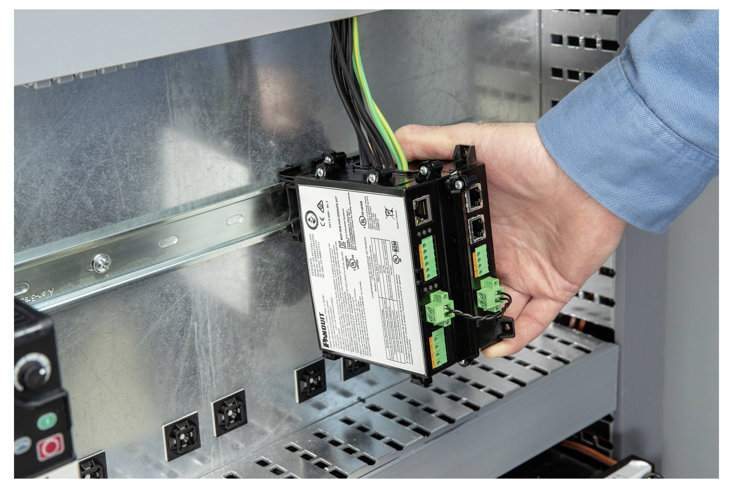 Eine Hand installiert ein industrielles elektronisches Modul auf einer Metalschiene innerhalb eines Schaltschranks.