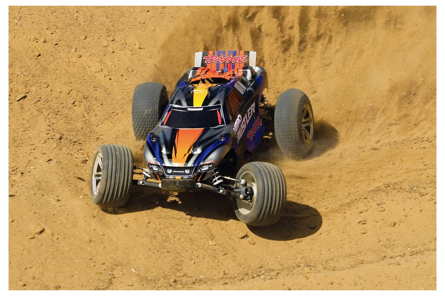 Ein ferngesteuertes Auto rast über eine Schotterpiste und wirbelt Staub auf, wobei seine robusten Reifen und dynamische Bewegung in einer Wüstenlandschaft zur Geltung kommen.