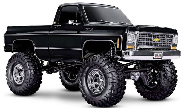 Ein schwarzer aufgehöhter Pickup-Truck mit überdimensionalen Reifen, mit einem Vintage-Design und einem markanten 'Chevrolet' Logo auf der Frontmaske.