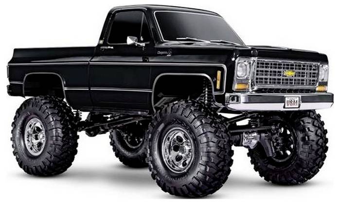 Ein angehobener schwarzer Vintage-Pickup-Truck mit großen Offroad-Reifen und einem Chrom-Kühlergrill, der auf einem weißen Hintergrund geparkt ist.