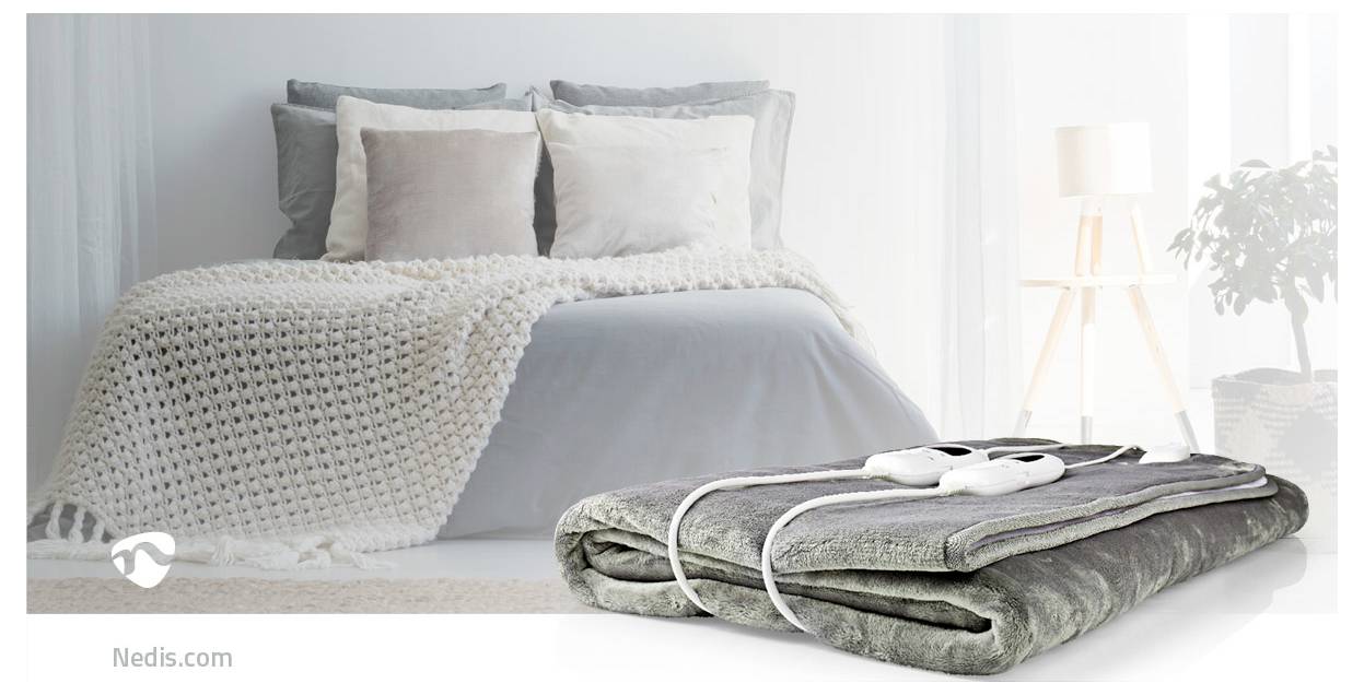 Ein gemachtes Bett mit Kissen und einer gestrickten Decke. Eine elektrische Decke mit Bedienungselementen ist seitlich zu sehen, was Wärme und Gemütlichkeit andeutet.
