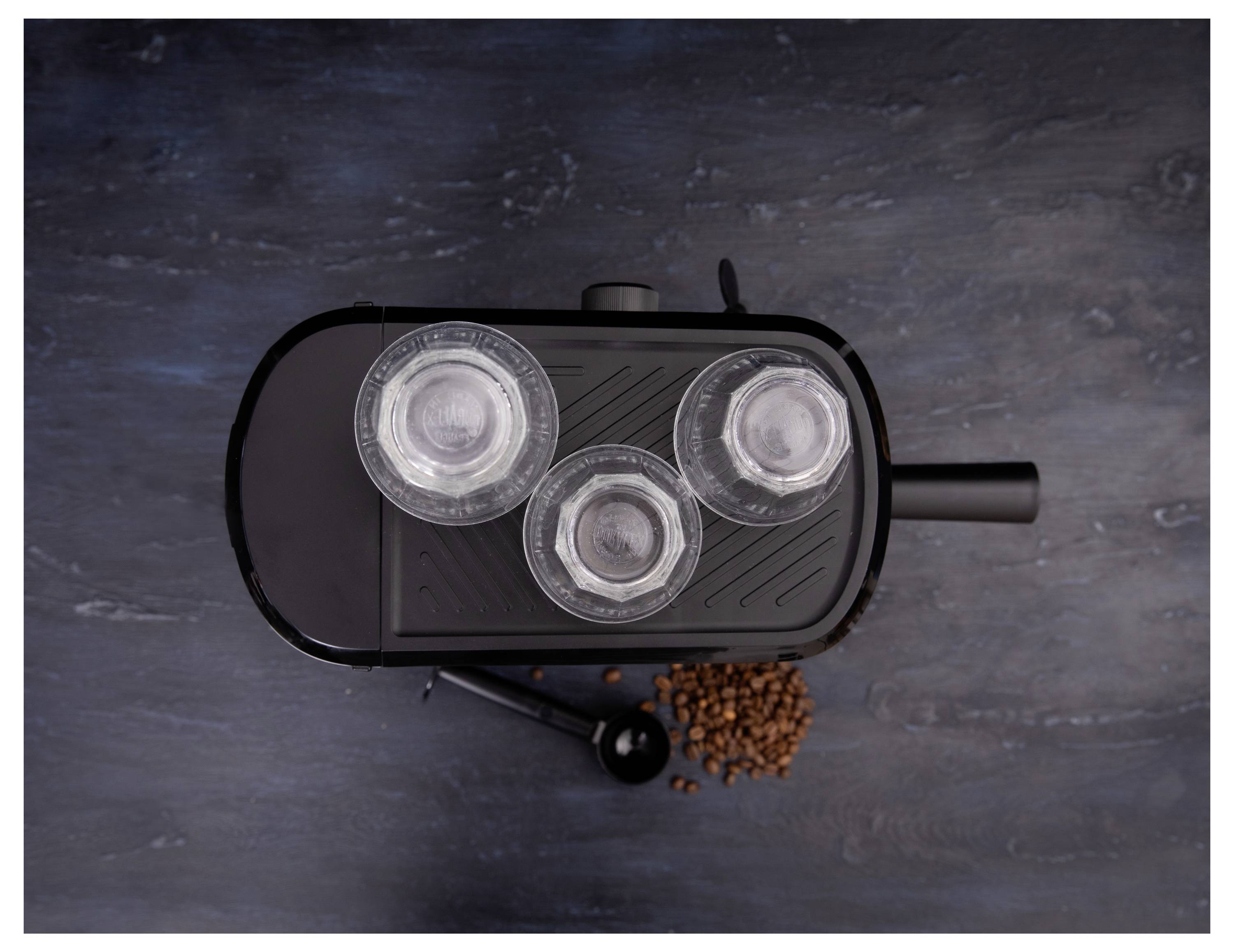 Draufsicht eines Kaffeemachers mit drei Glasschalen auf einer Schieferoberfläche, umgeben von verstreuten Kaffeebohnen.