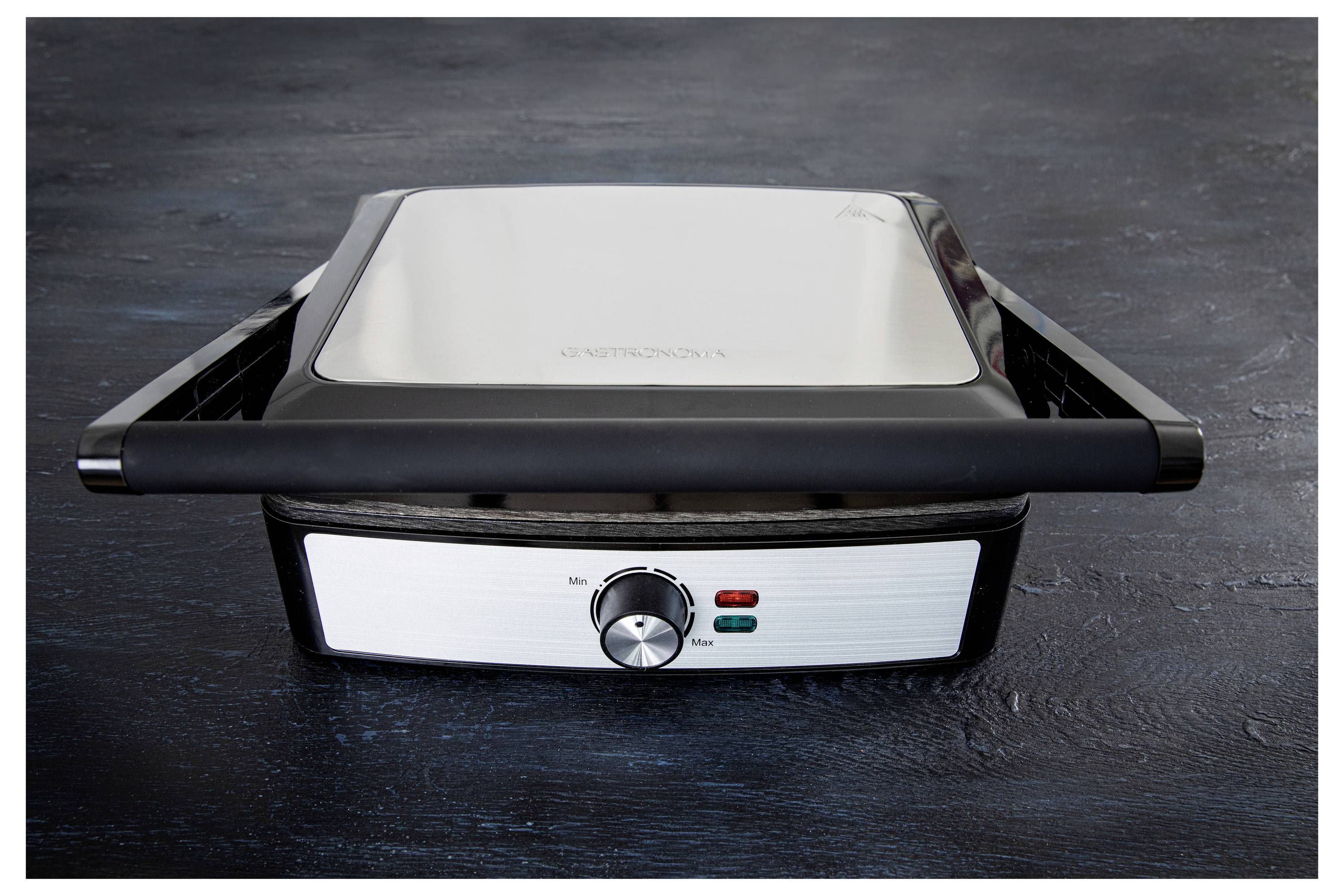 Ein geschlossener elektrischer Edelstahlgrill auf einer dunklen Oberfläche, ausgestattet mit einem Temperaturregler und Kontrollleuchten.