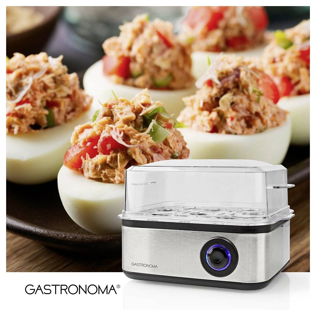 Eierkocher der Marke 'Gastronoma' unter einer Platte mit Deviled Eggs, die mit einer Lachs-Tomaten-Mischung garniert sind.