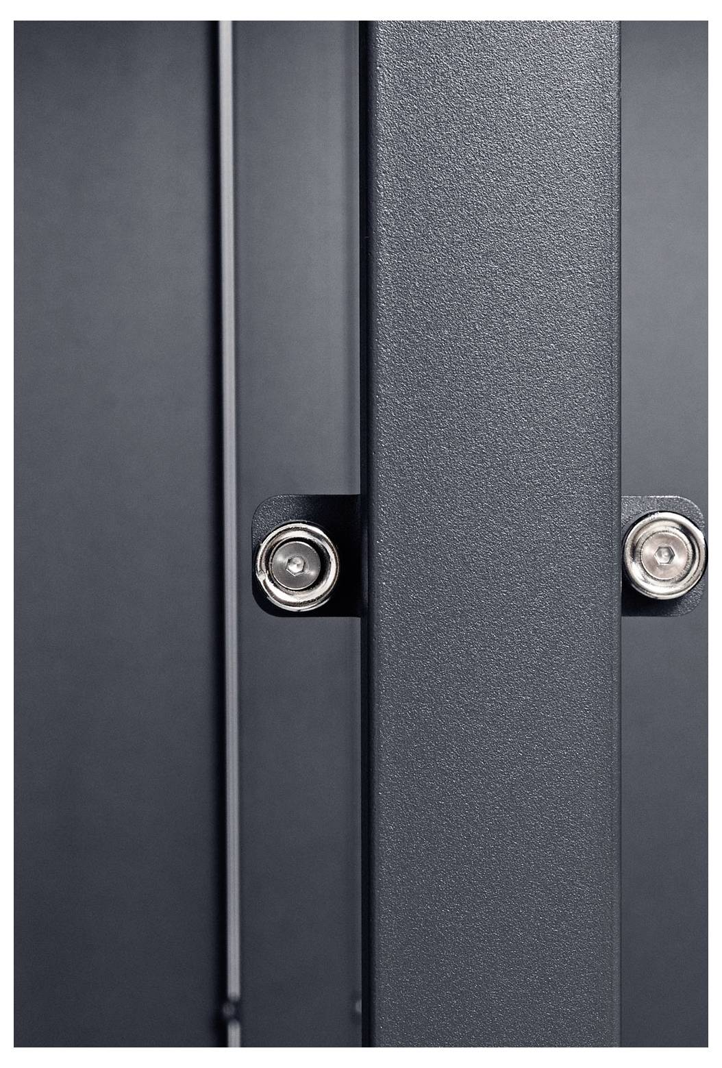 Eine Nahaufnahme einer grauen Metallstruktur mit Bolzen und sichtbaren vertikalen Paneelen im Hintergrund.