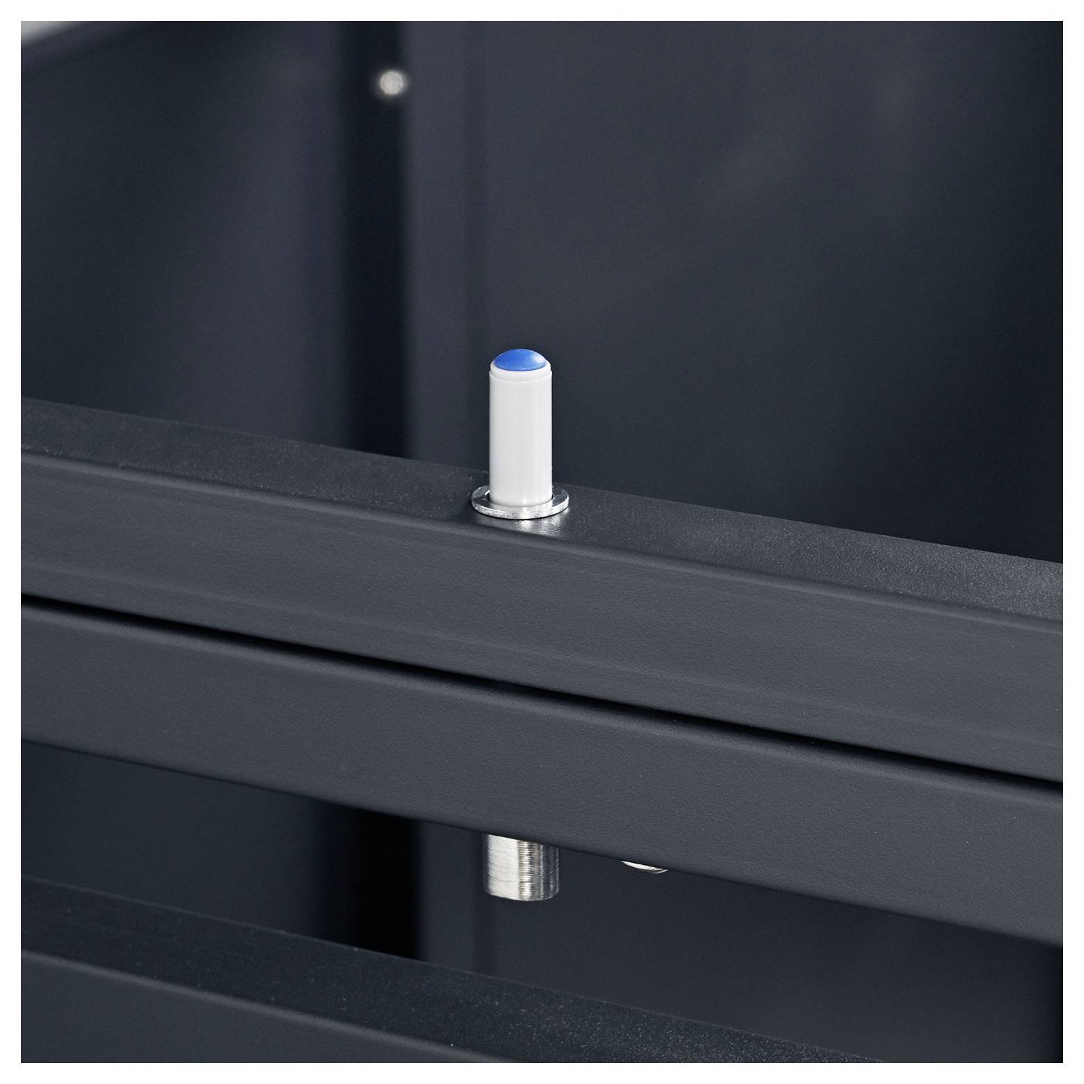 Nahaufnahme eines kleinen vertikalen weißen Kunststoffstifts mit blauer Spitze auf einem dunklen Metallrahmen, wahrscheinlich zur Positionierung oder Ausrichtung verwendet.