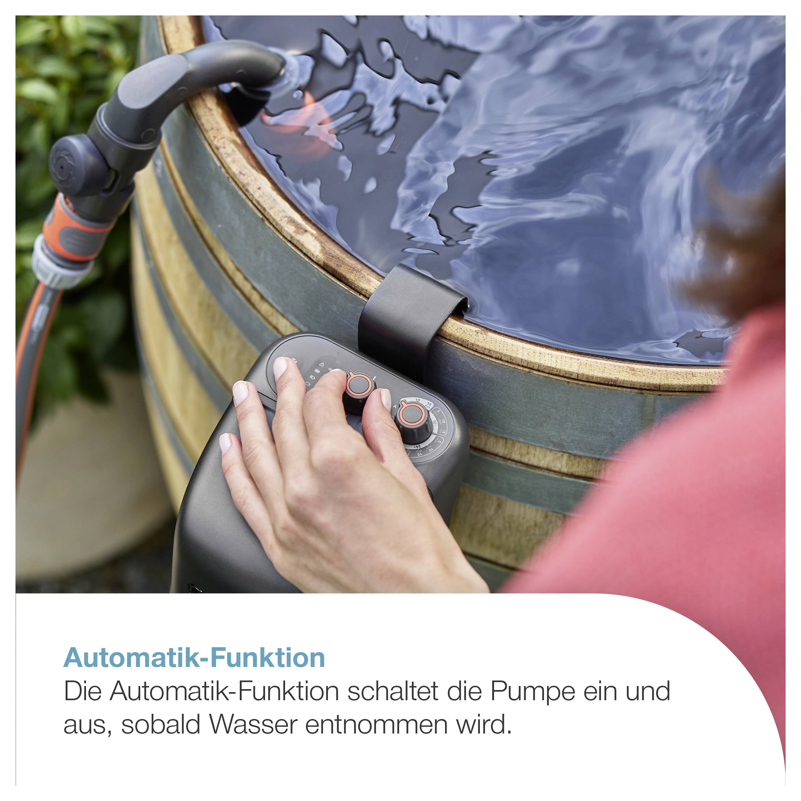 Hand bedient die Steuerung einer Regenwasserpumpe am Wasserfass; Beschriftung: 'Automatik-Funktion'. Die Pumpe schaltet beim Wasserentnehmen ein und aus.