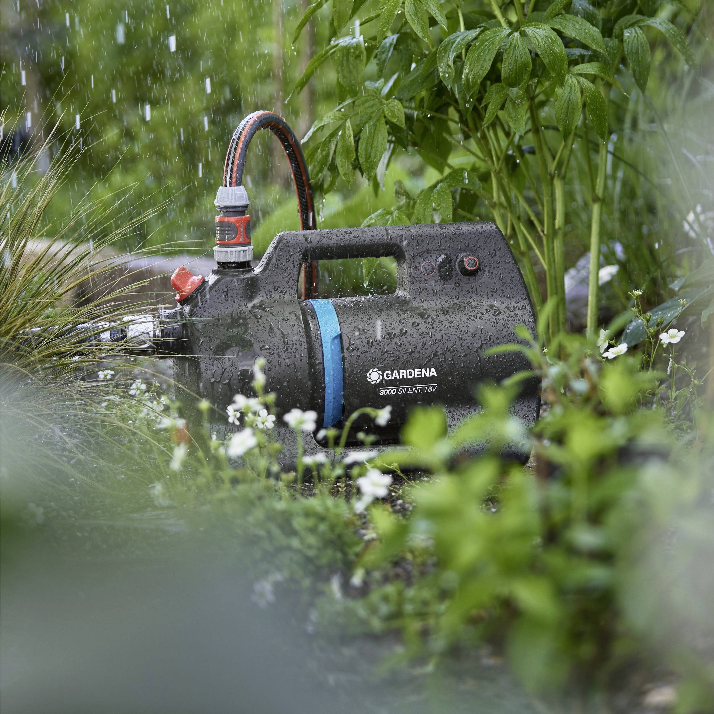 Ein Gartenwasserpumpe inmitten üppiger grüner Pflanzen, mit Wassertröpfchen, die eine aktive Bewässerung anzeigen.