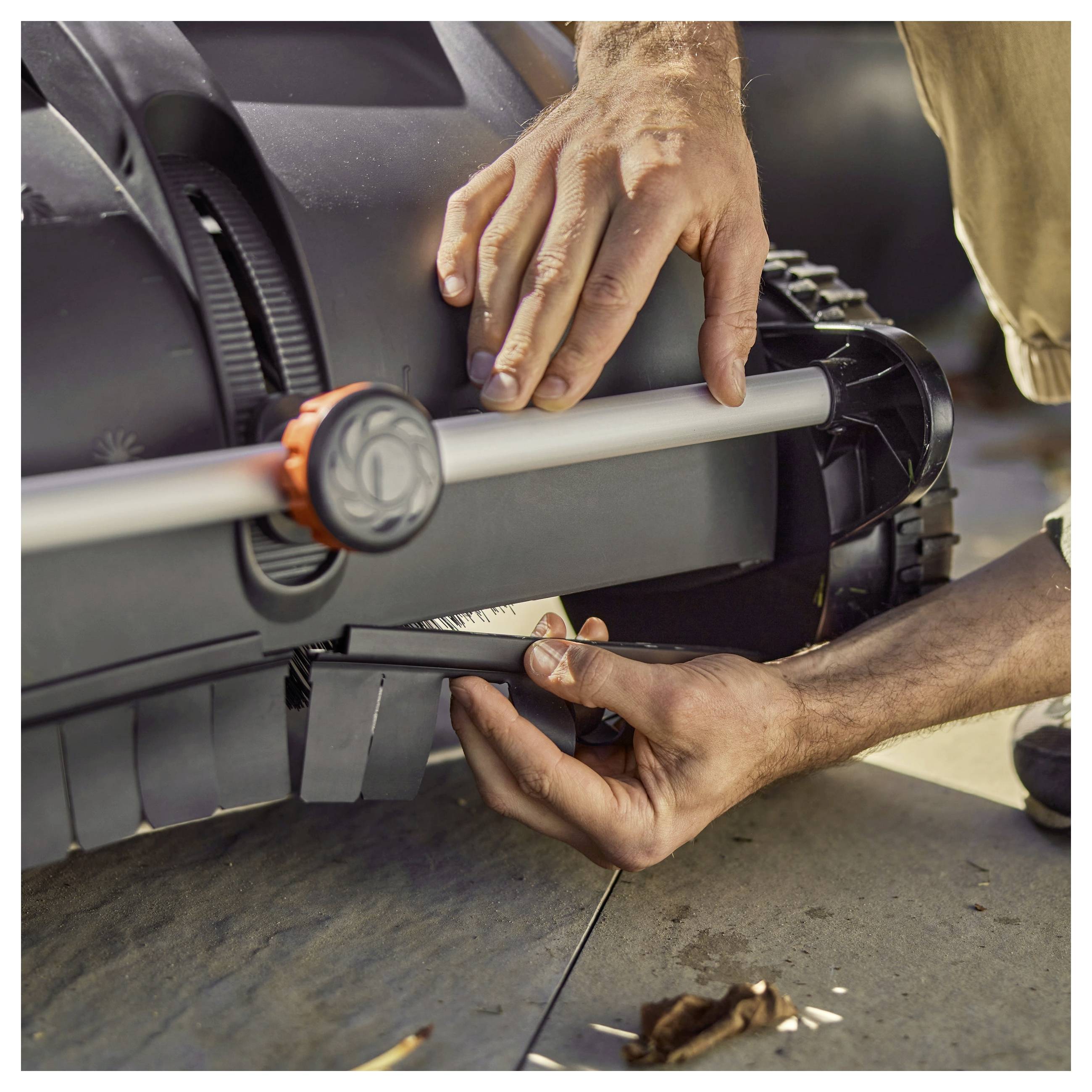 Eine Person stellt die Einstellungen an einem Rasenmäher ein und konzentriert sich dabei auf den Griff bereich, was auf Wartung oder Vorbereitung für die Verwendung hindeutet.