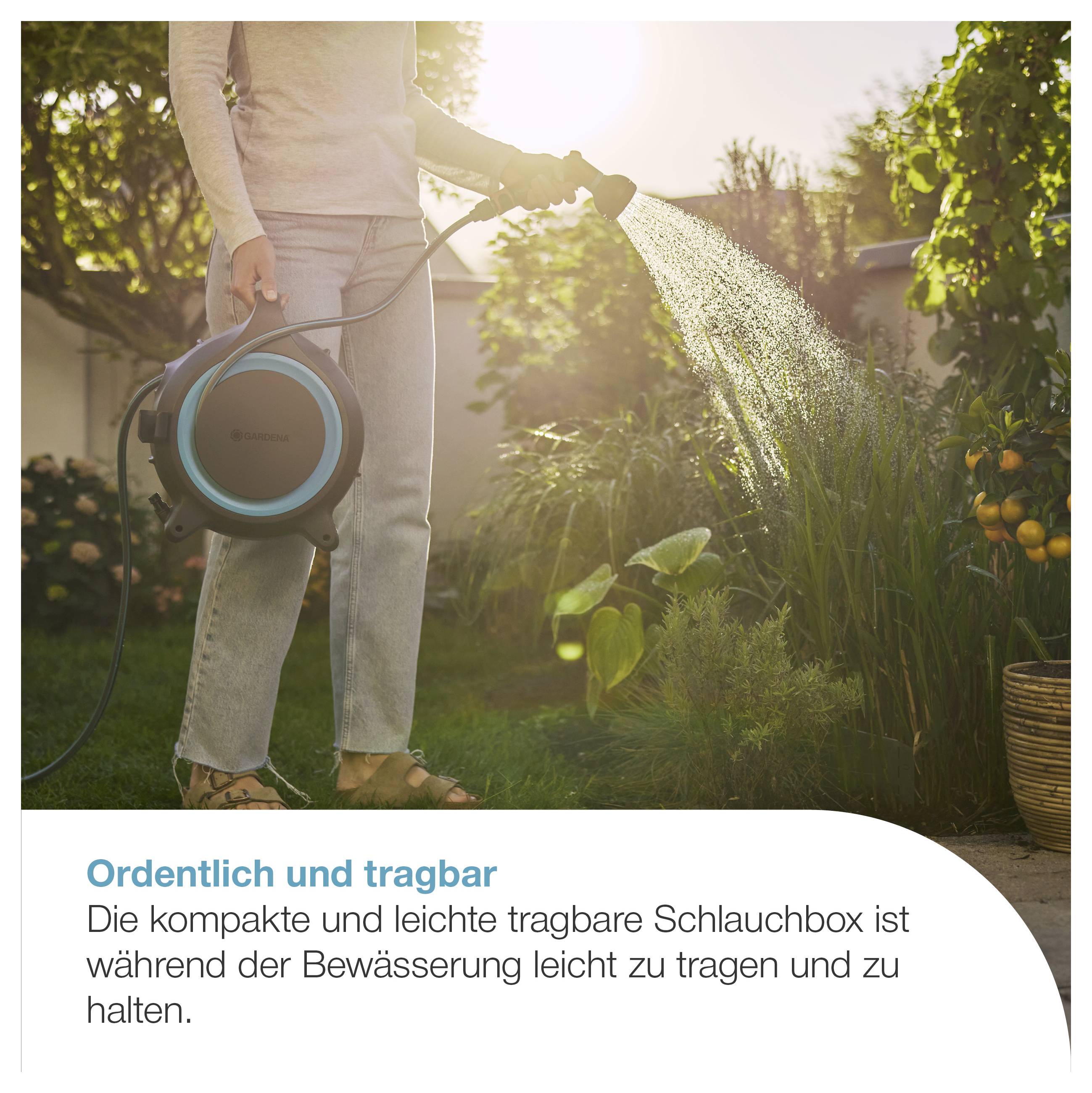 Person gießt im Garten mit tragbarer Schlauchbox; die kompakte, leichte Box ist gut zu tragen und zu halten.