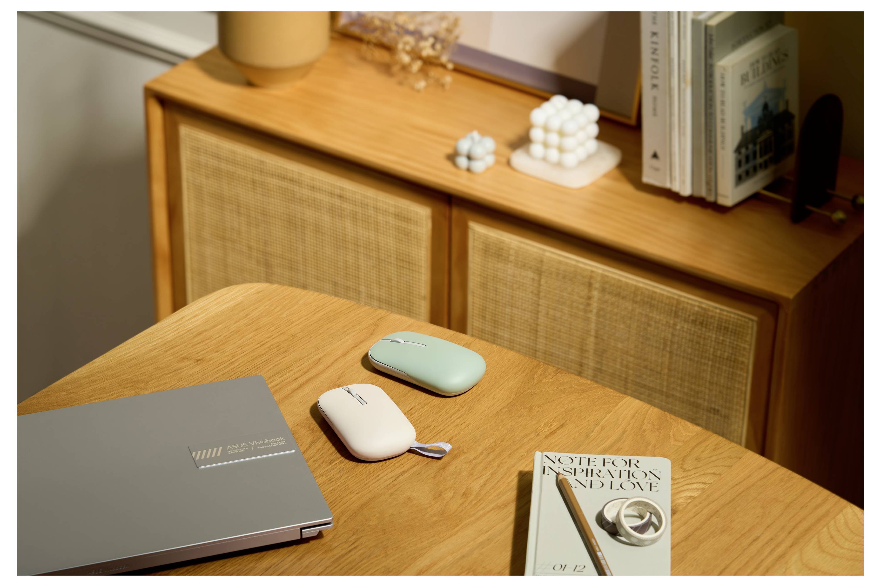 Ein Holzschreibtisch mit zwei tragbaren elektronischen Geräten, einem Buch mit dem Titel „Notizbuch-Inspirationen und Liebe