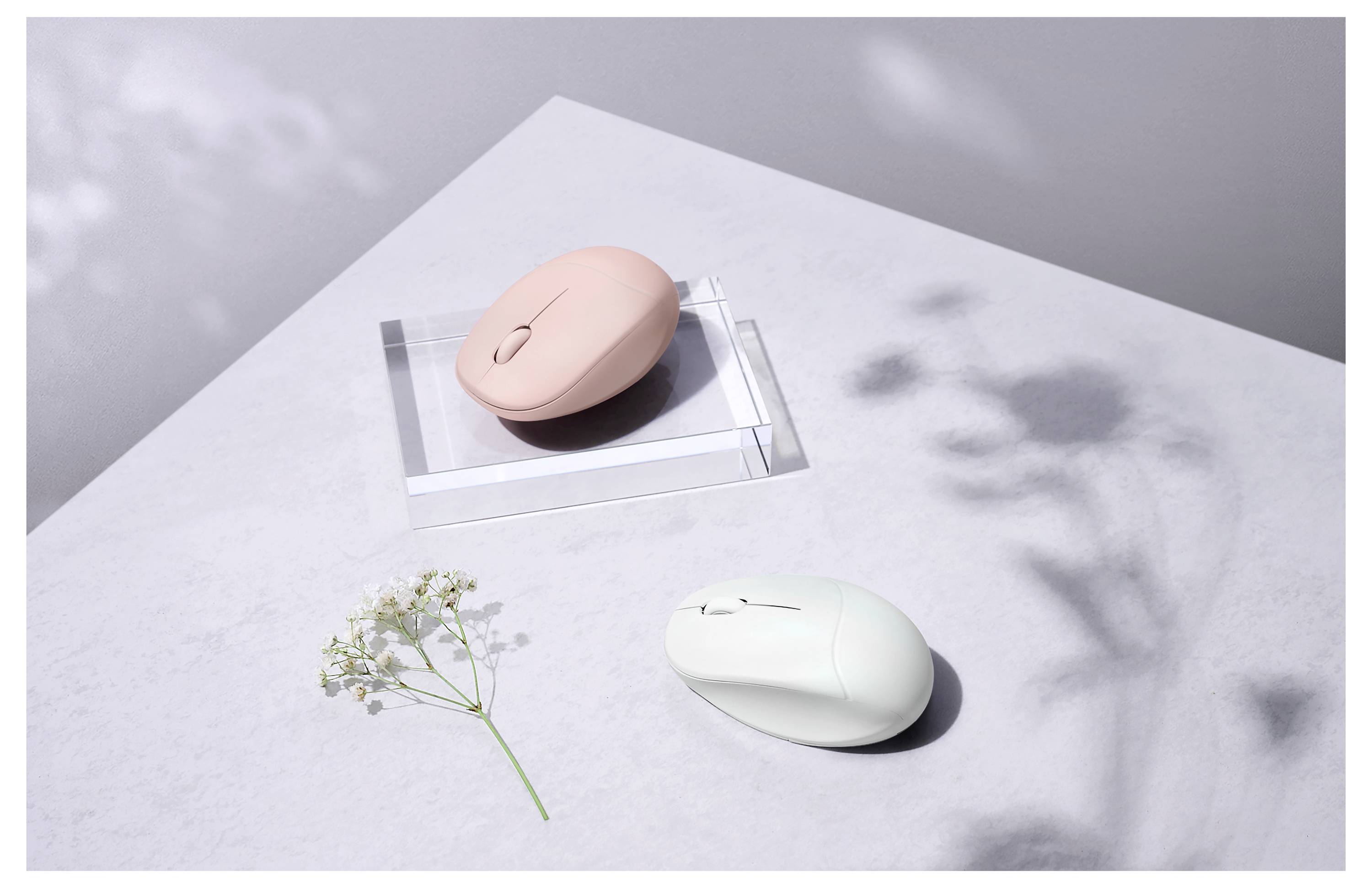 Eine weiche rosa-weiße Computermaus auf einer hellgrauen Oberfläche mit einer kleinen Blume und einem Schatten, was einen minimalistischen und eleganten Stil andeutet.