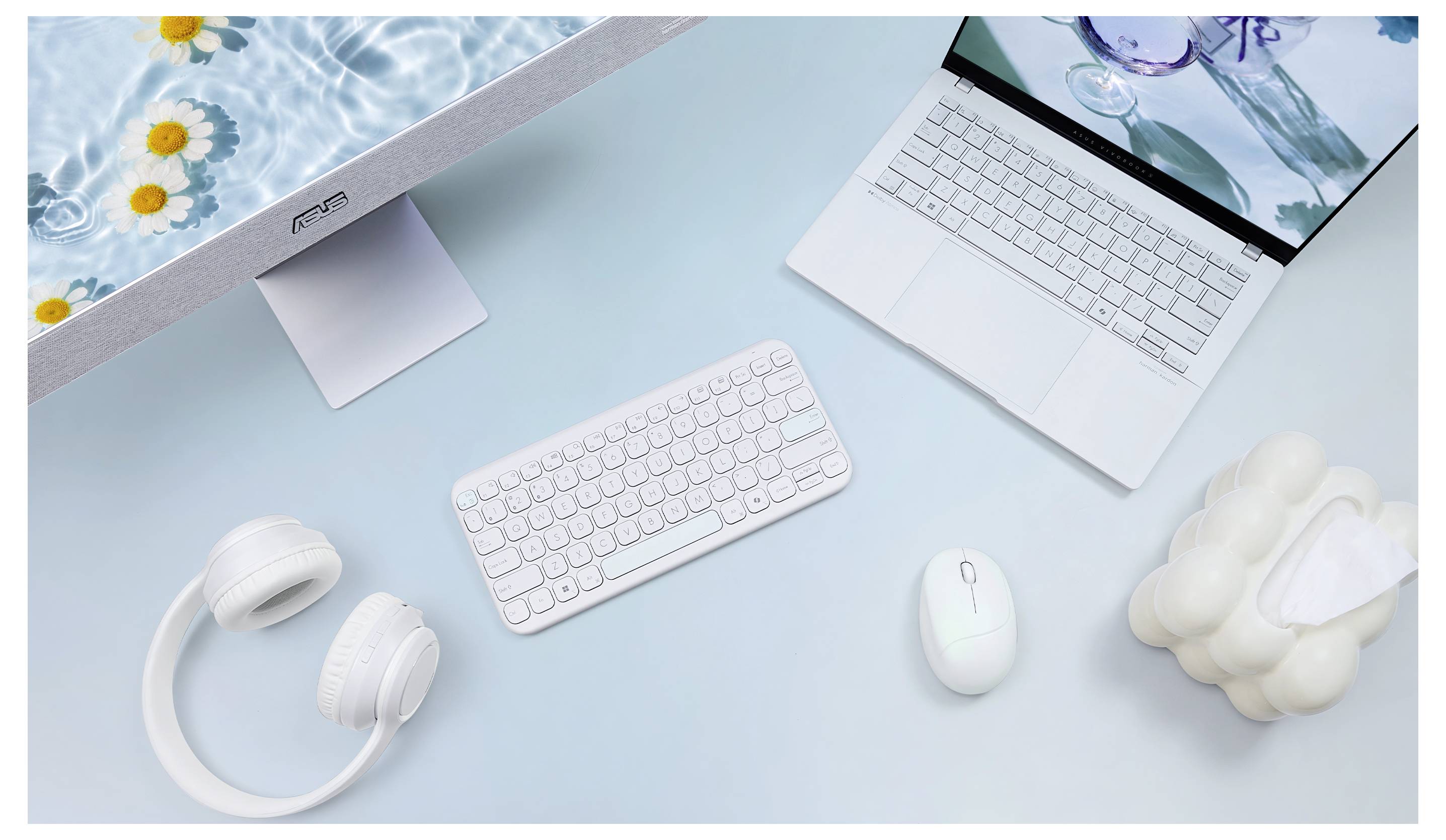Ein ordentlich angeordneter Arbeitsplatz mit einem Laptop, Tastatur, Maus und weißen Kopfhörern auf einer pastellblauen Oberfläche, mit Gänseblümchen in Wasser auf dem Bildschirm.