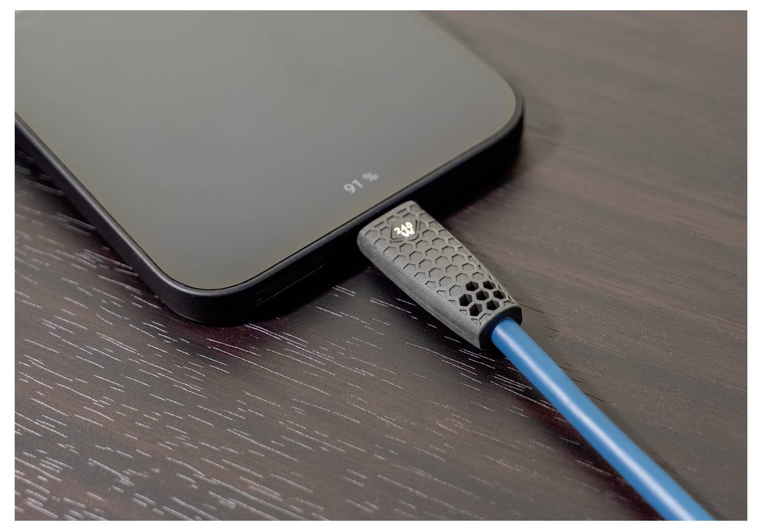 Ein Smartphone lädt auf einer Holzoberfläche, verbunden durch ein blaues Ladekabel. Der Bildschirm zeigt eine Akkukapazität von 91%.