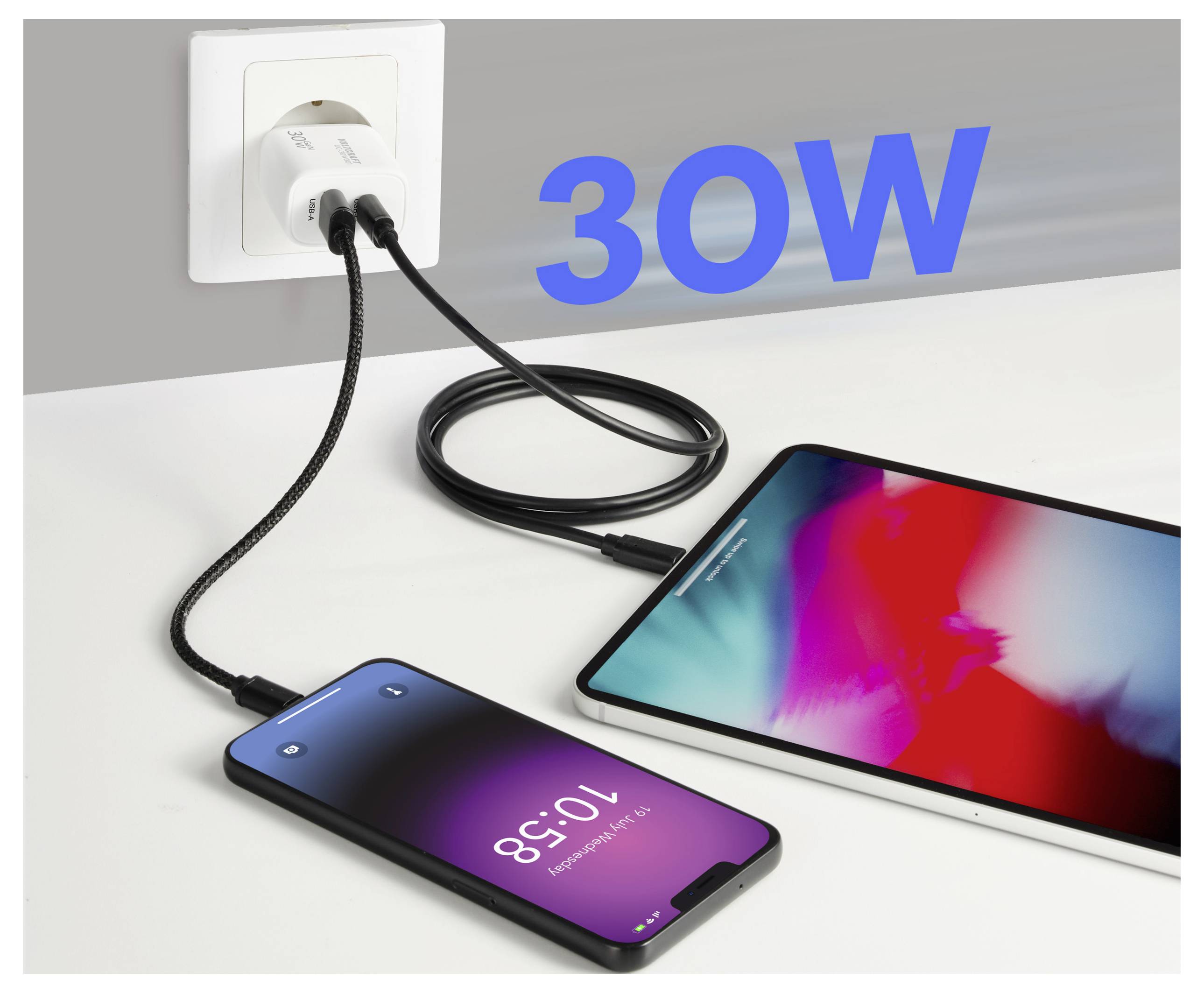 Ein Smartphone und Tablet werden an einer Wandsteckdose mit einem 30W-Ladegerät aufgeladen. Die Geräte leuchten auf und zeigen an, dass aktiv geladen wird.