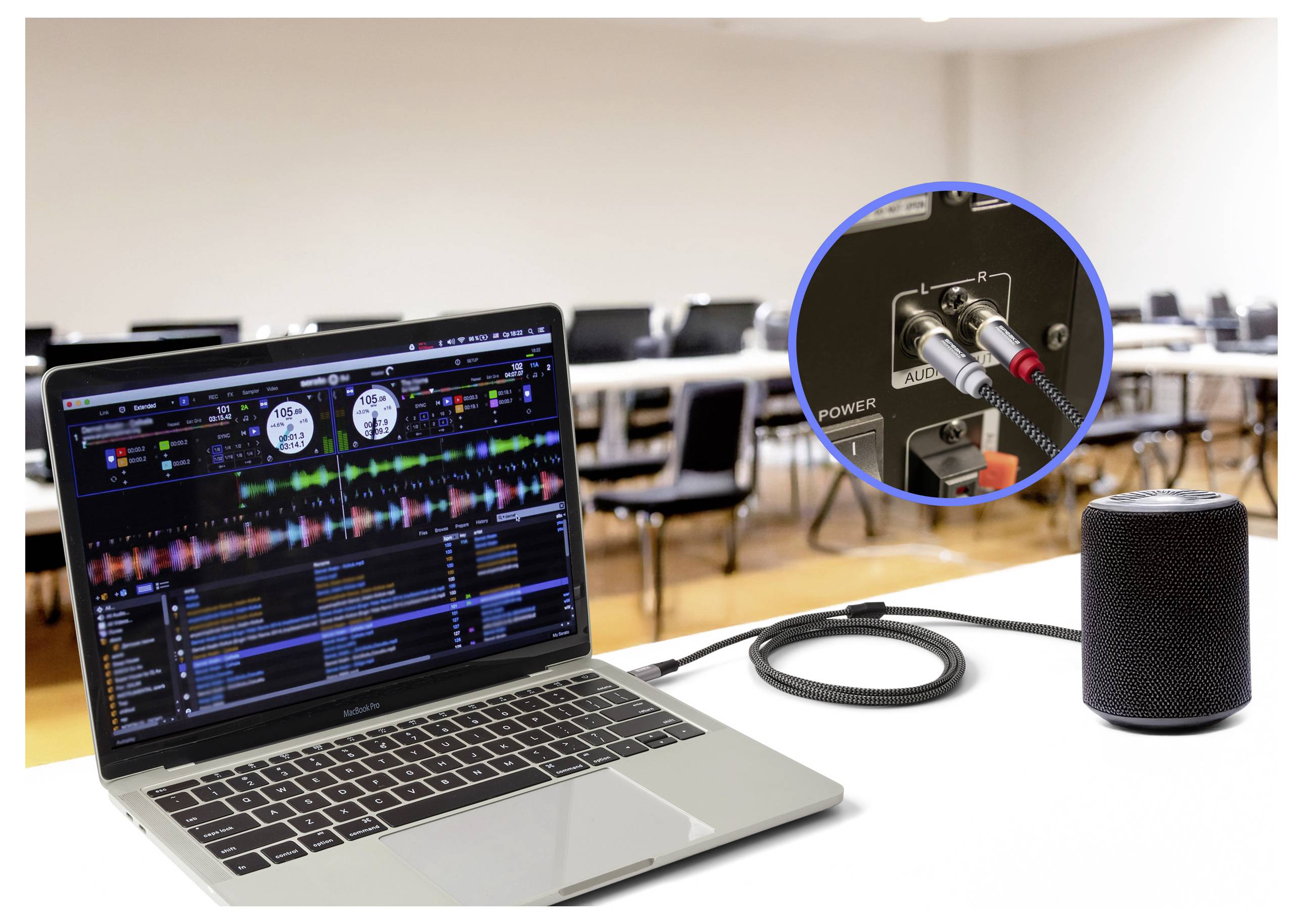 Ein Laptop, auf dem DJ-Software angezeigt wird, ist in einem Klassenzimmer mit einem Lautsprecher verbunden. Ein Einschub zeigt Audiokabel, die in die Rückseite des Lautsprechers eingecheckt sind.
