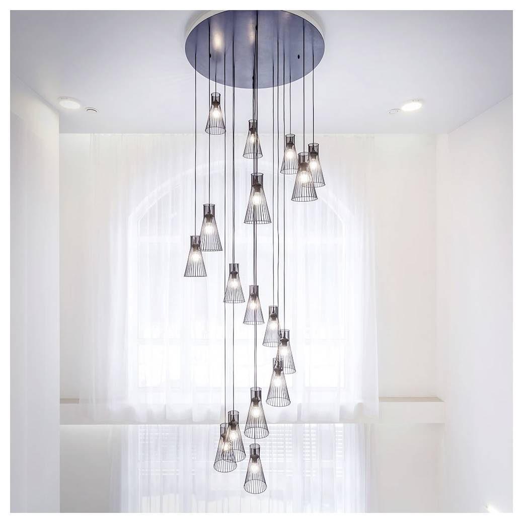 Moderner Kronleuchter mit mehreren Pendelleuchten, die in einem Spiralmuster hängen, vor einem sanft beleuchteten weißen Raum mit transparenten Gardinen.