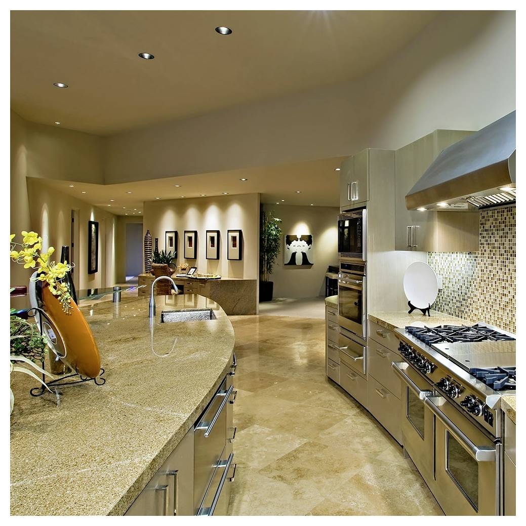 Moderne Küche mit Edelstahl-Haushaltsgeräten, Granitarbeitsflächen und Fliesenrückwand. Essbereich mit dekorativer Wandkunst im Hintergrund sichtbar.