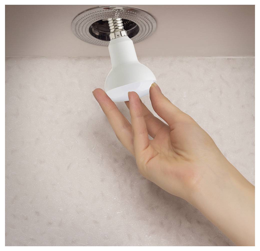 Eine Hand montiert eine Glühbirne in eine Deckenlampe und demonstriert den Vorgang des Glühbirnenwechsels in einer Standard-Leuchte.