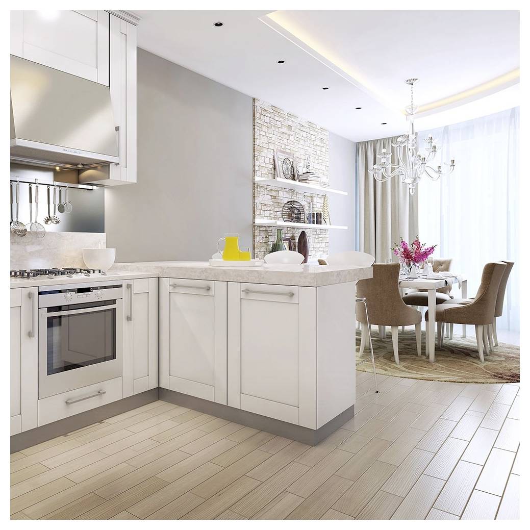 Eine moderne Küche mit weißen Schränken und beigen Arbeitsplatten öffnet sich zu einem Essbereich mit einem für vier Personen gedeckten Tisch. Ein Kronleuchter hängt über dem Tisch.