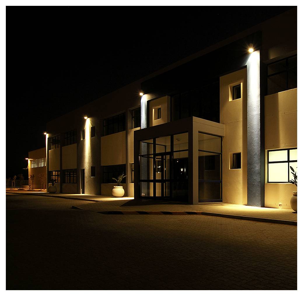 Modernes Gebäudeäußeres bei Nacht, beleuchtet von Lichtern, mit einem großen Glaseingang.