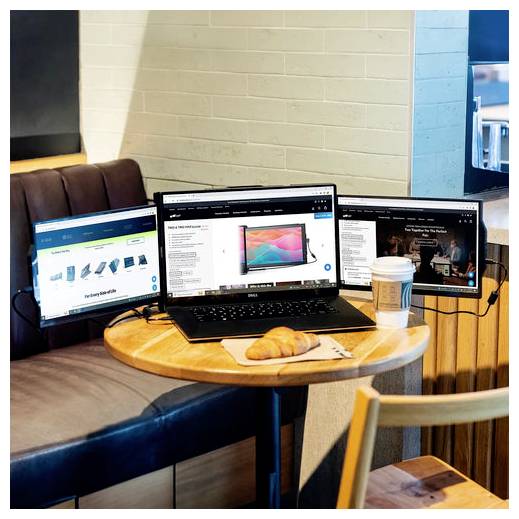 Ein Laptop mit zwei zusätzlichen Monitoren an einem runden Tisch in einem Café. Ein Croissant und eine Kaffeetasse stehen auf dem Tisch, mit Ziegelwand im Hintergrund.