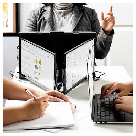 Drei Personen arbeiten an einem Tisch mit Laptops und Dokumenten. Eine Person zeigt auf einen Bildschirm mit Marketinggrafiken, während eine andere Notizen macht.