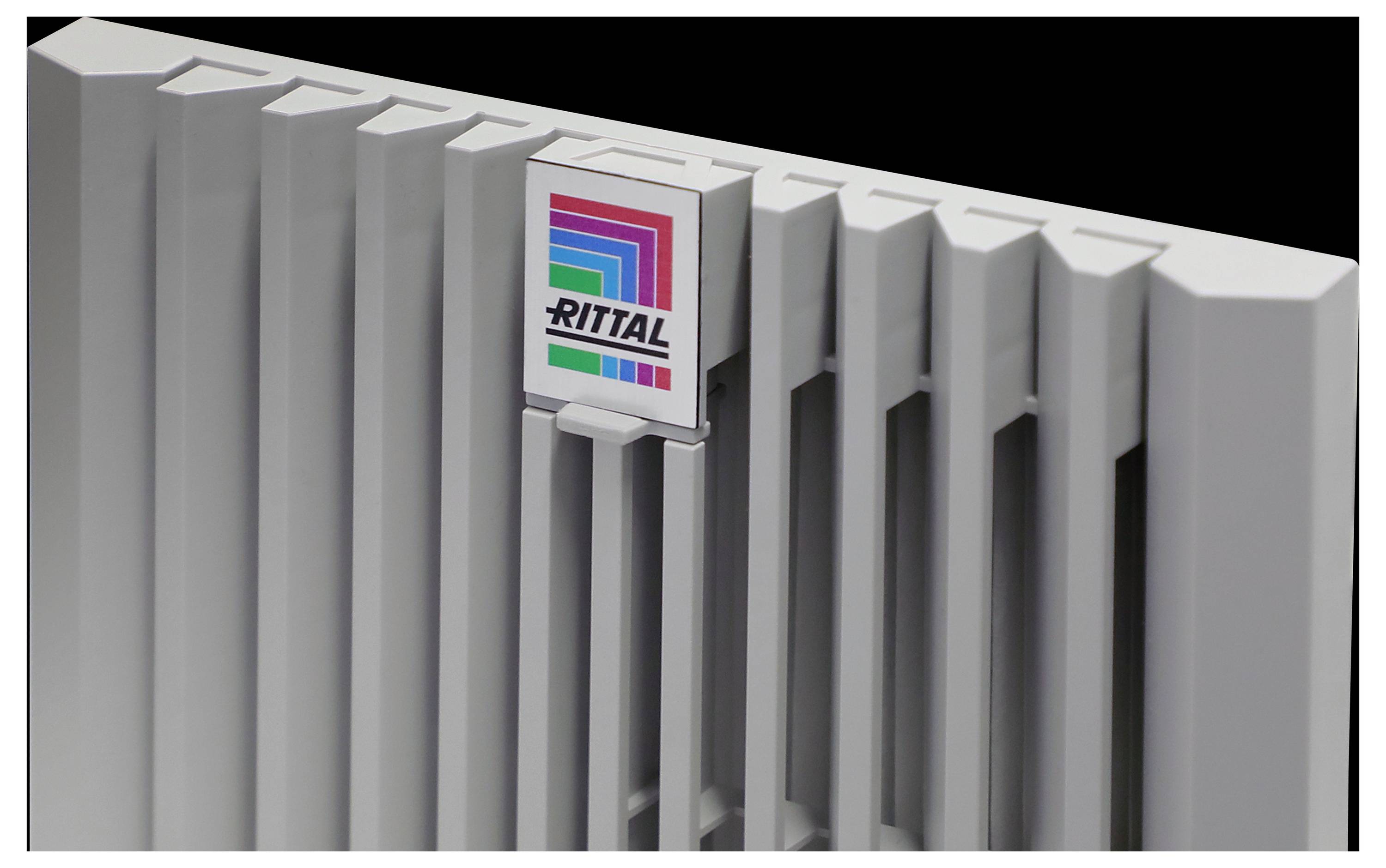 Eine Nahaufnahme eines grauen Rittal-Gehäusepanels mit vertikalen Lüftungsschlitzen und dem Rittal-Logo mit mehrfarbigen Streifen auf einem dunklen Hintergrund.
