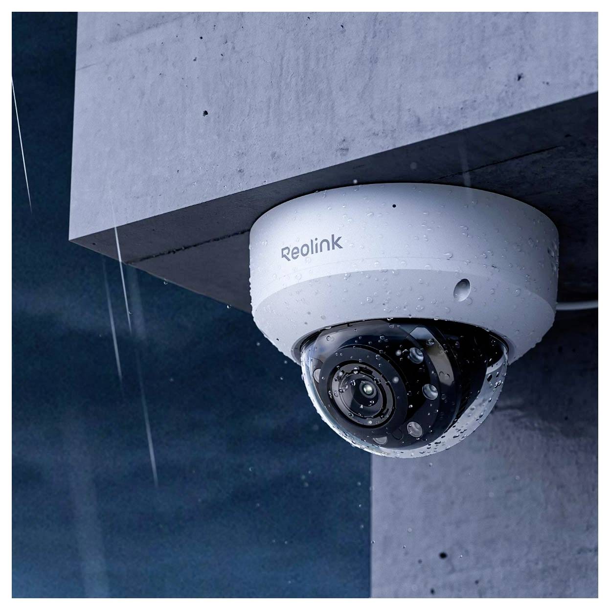 Eine Überwachungskamera, die an der Ecke eines Gebäudes montiert ist, wird bei regnerischem Wetter gezeigt, wobei ihr wasserresistentes Design hervorgehoben wird.