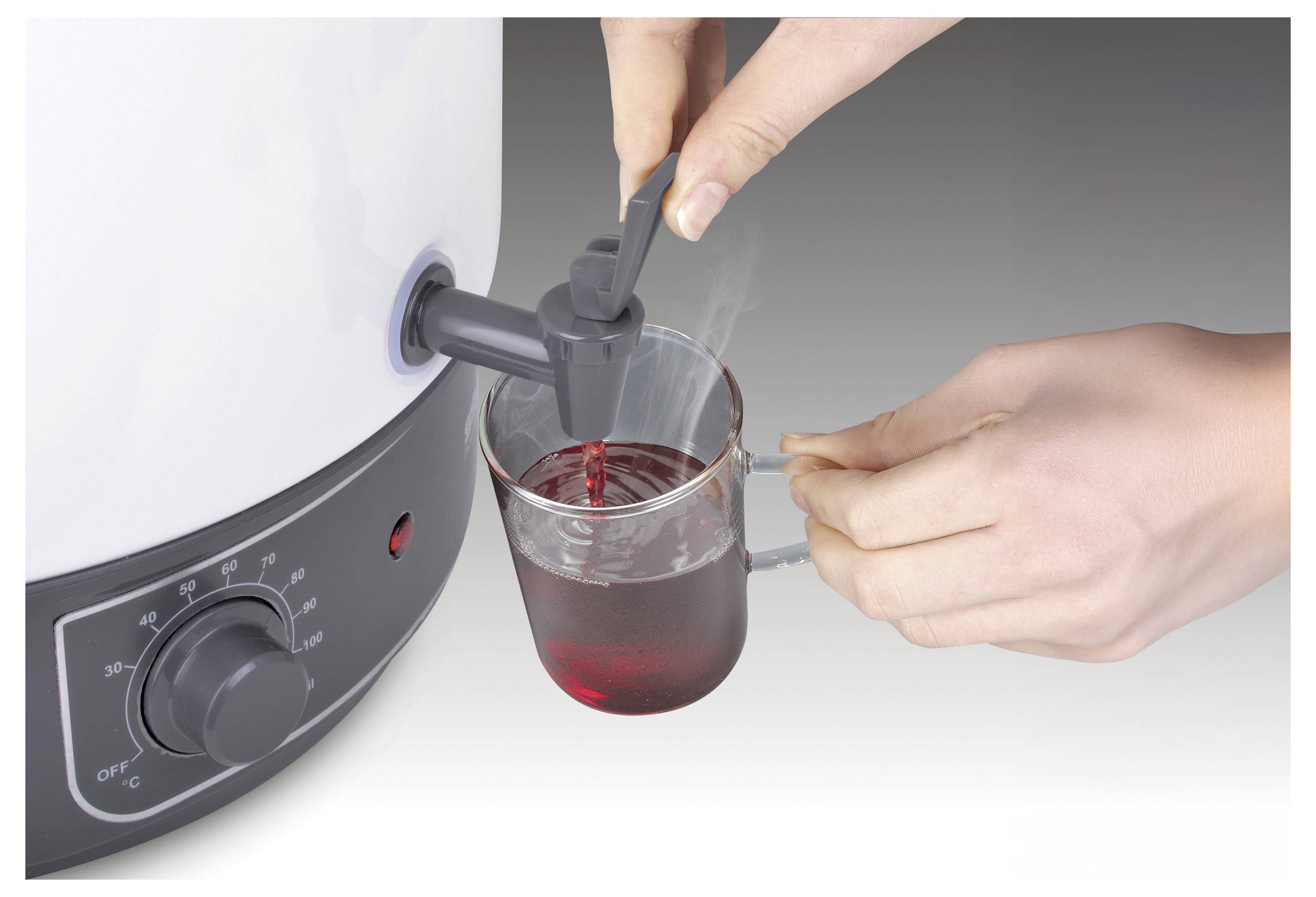 Eine Hand eines Menschen gibt ein heißes Getränk aus einem beheizten Behälter in einen durchsichtigen Becher. Der Einstelldrehknopf des Behälters ist auf mittlerer Temperatur eingestellt.