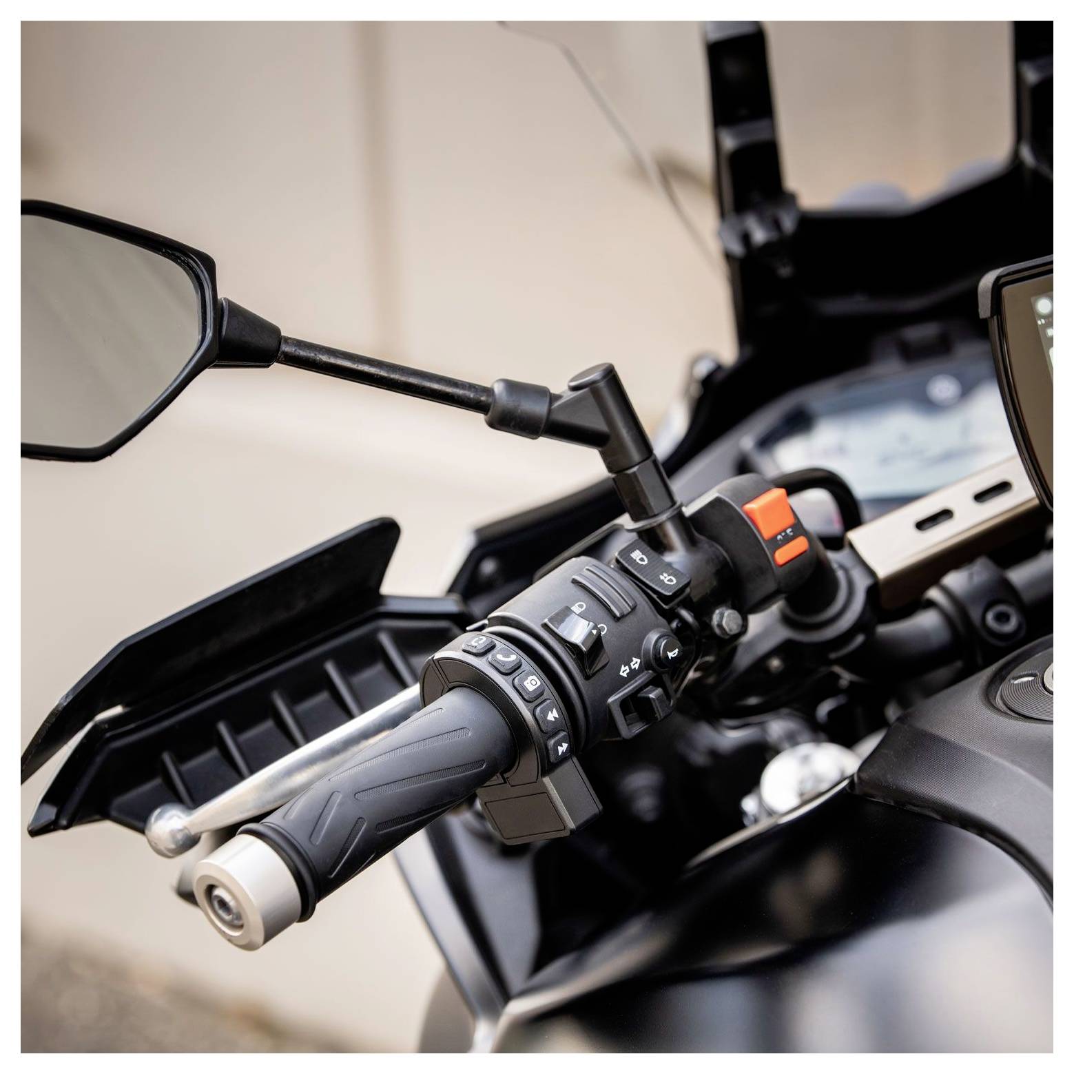 Nahaufnahme eines Motorradlenkrads mit verschiedenen Bedienelementen, einschließlich Tasten und Schaltern, zusammen mit einem Seitenspiegel und einem Teil des Armaturenbretts.